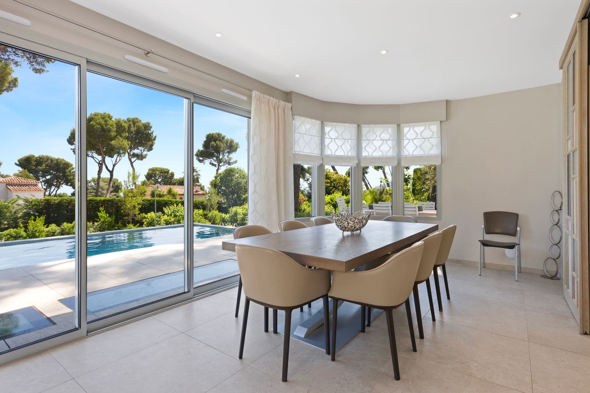 Dining table for eight beside full-height windows onto the pool at Above Antibes