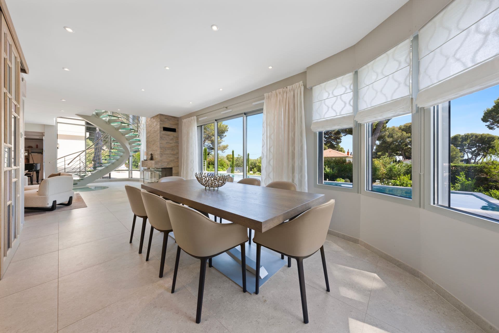 Dining area with the glass staircase behind and a distant sea view at Above Antibes