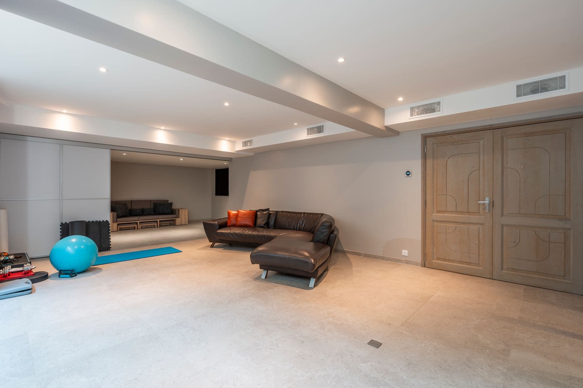 Lower-ground games and media room with sofas and open floor space at Above Antibes