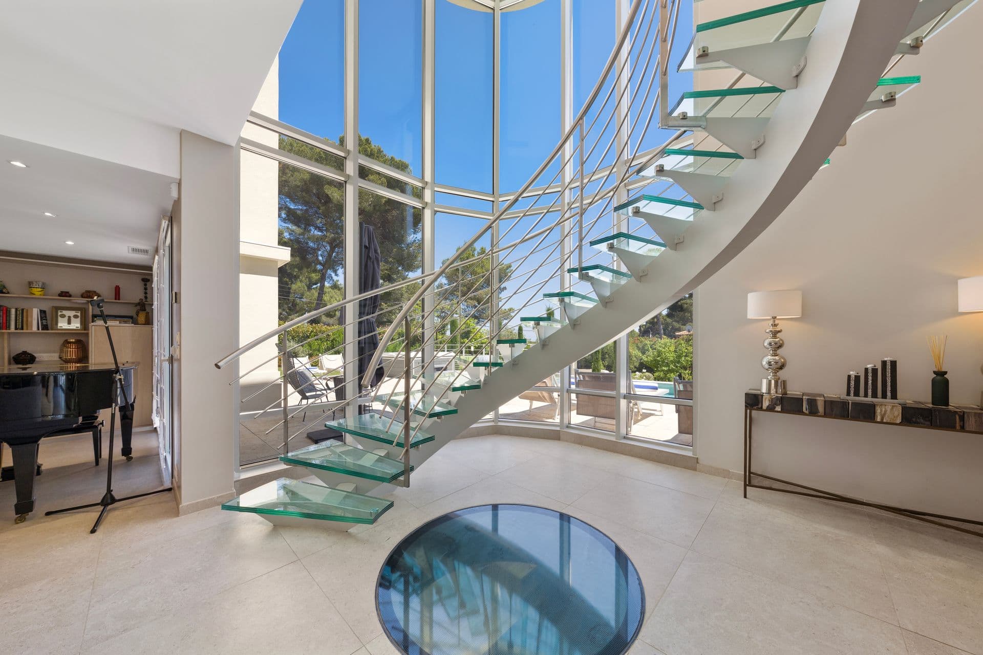 Sculptural glass spiral staircase beside a grand piano at Above Antibes, Cap d'Antibes