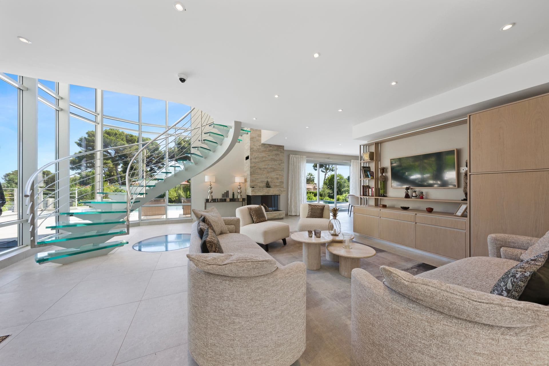 Open-plan living room with a stone fireplace, television and the glass staircase at Above Antibes