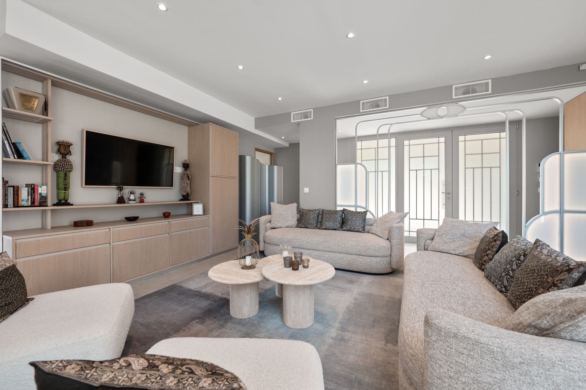 Pale-toned lounge with curved sofas and a television at Above Antibes, Cap d'Antibes