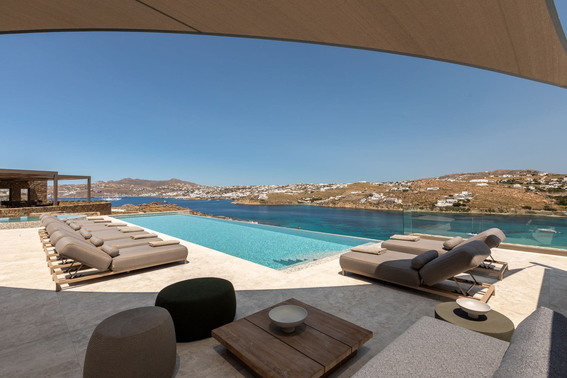 Infinity pool and sun loungers overlooking the bay at Aegean Aspect, Mykonos, Greece