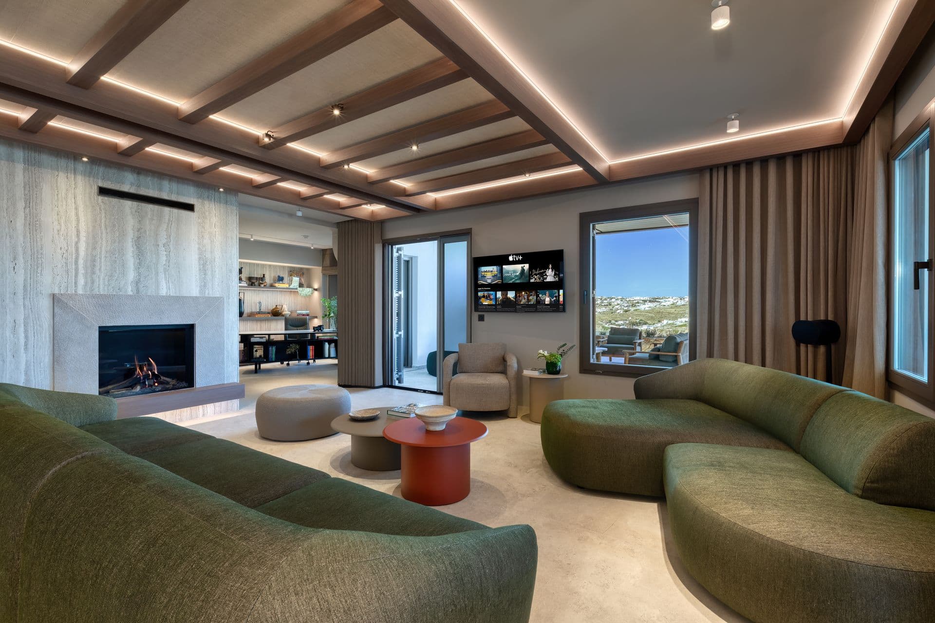 Living room with a travertine fireplace, green sofas and sea views at Aegean Aspect, Mykonos