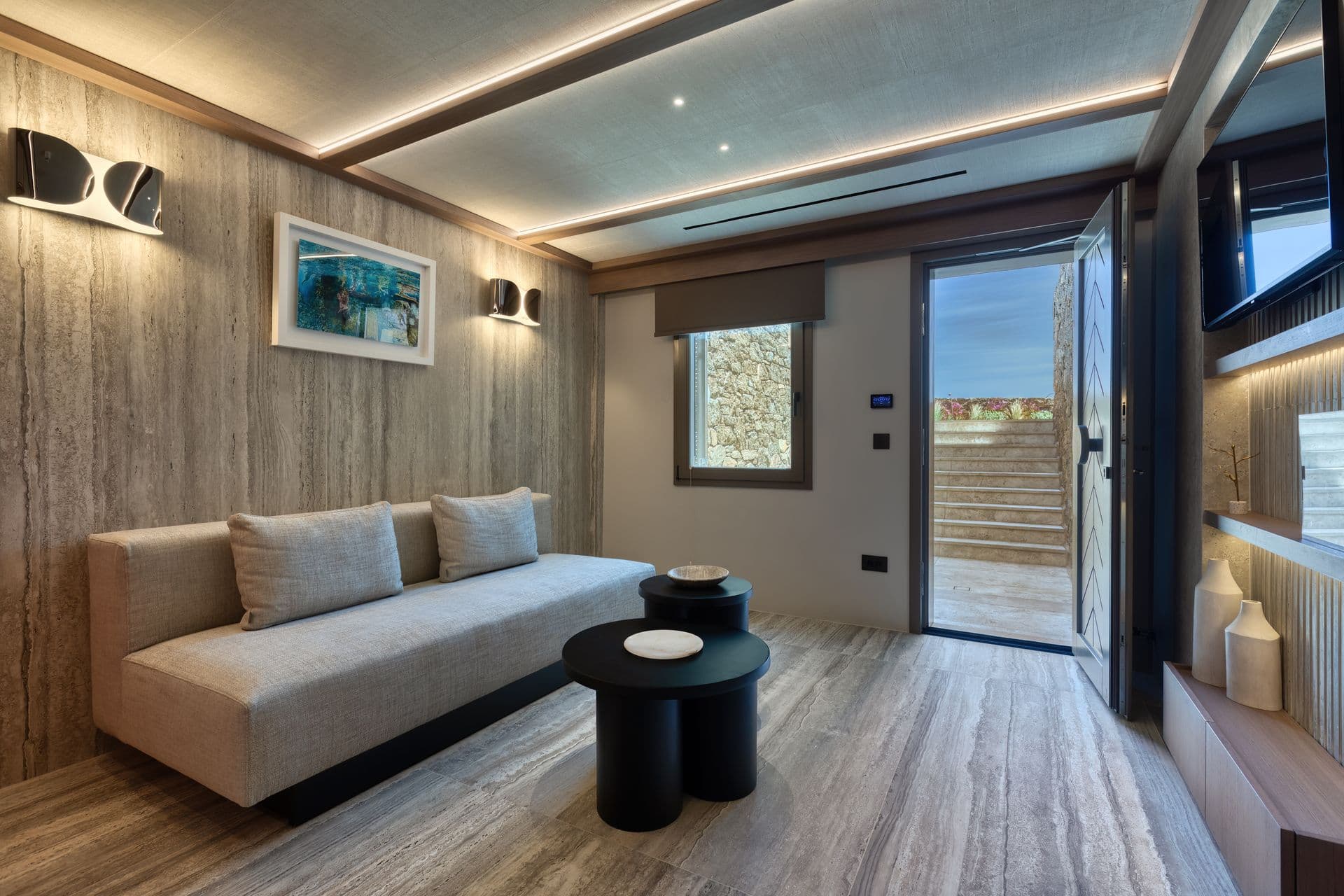 Media snug with a grey sofa opening to a terrace at Aegean Aspect, Mykonos