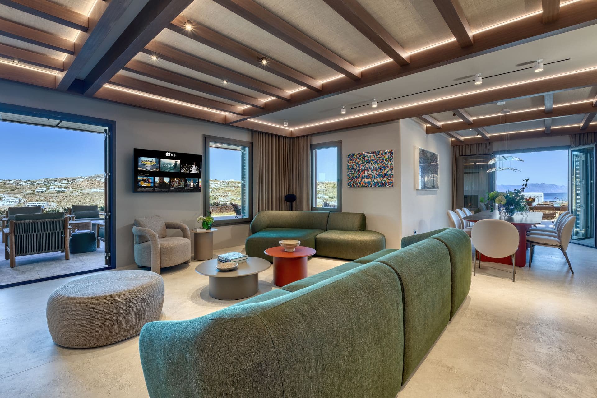 Open-plan living and dining space with a green sofa and timber ceiling at Aegean Aspect, Mykonos