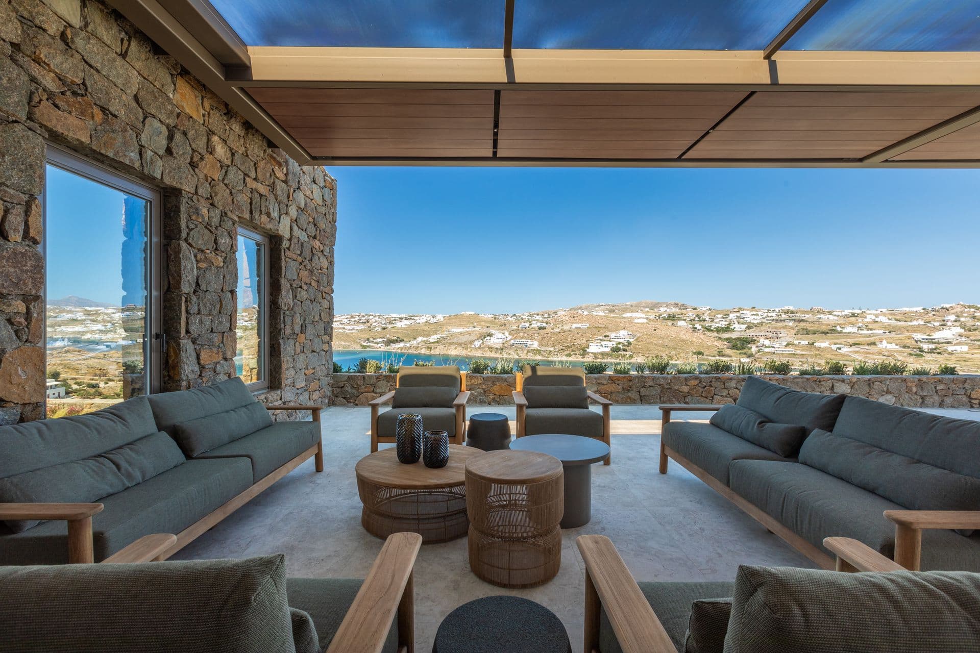 Covered outdoor lounge with deep sofas facing the Mykonos hills at Aegean Aspect