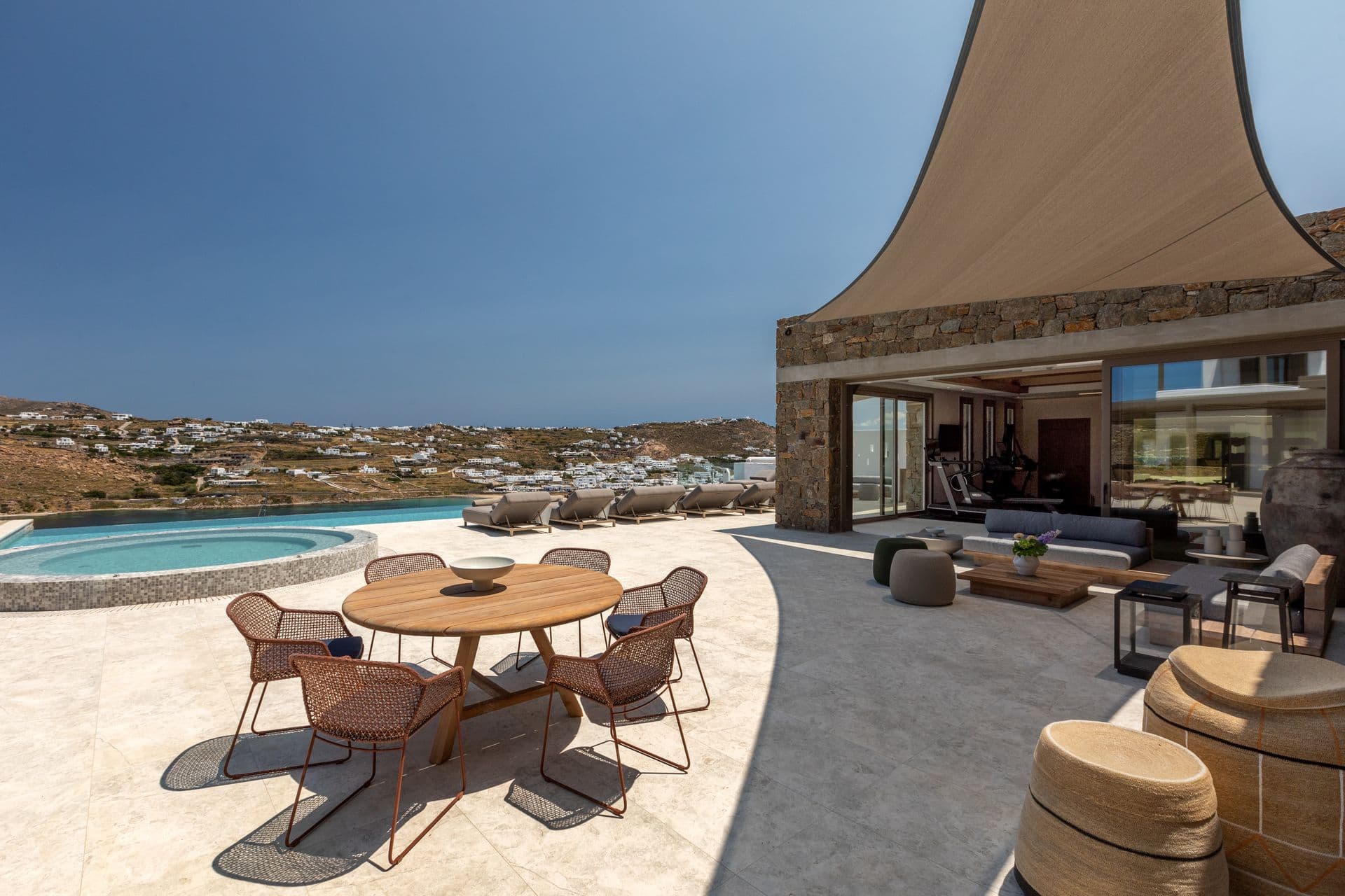Round outdoor dining table beside the pool under a shade sail at Aegean Aspect, Mykonos