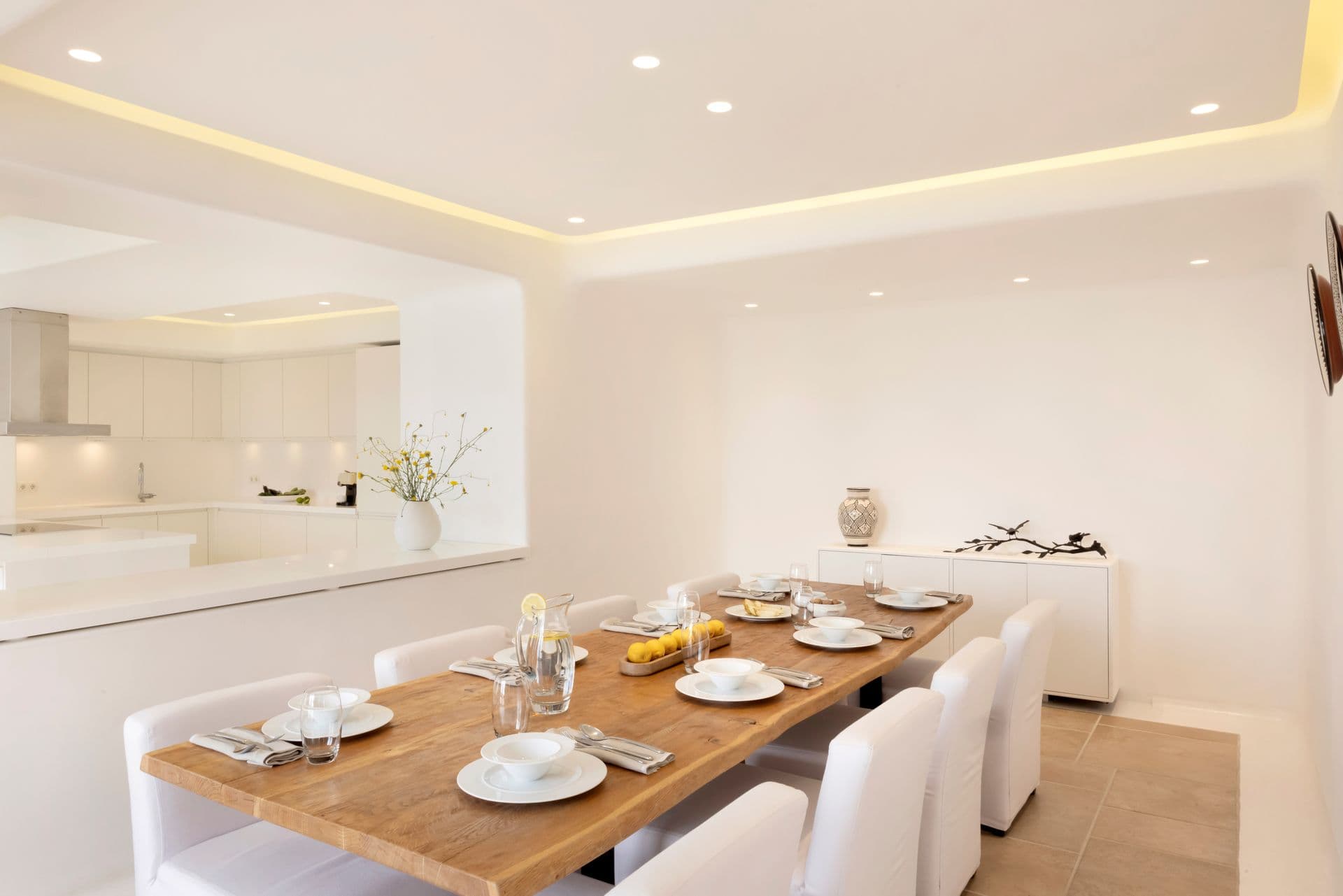 Indoor dining table set for eight adjacent to the open-plan kitchen