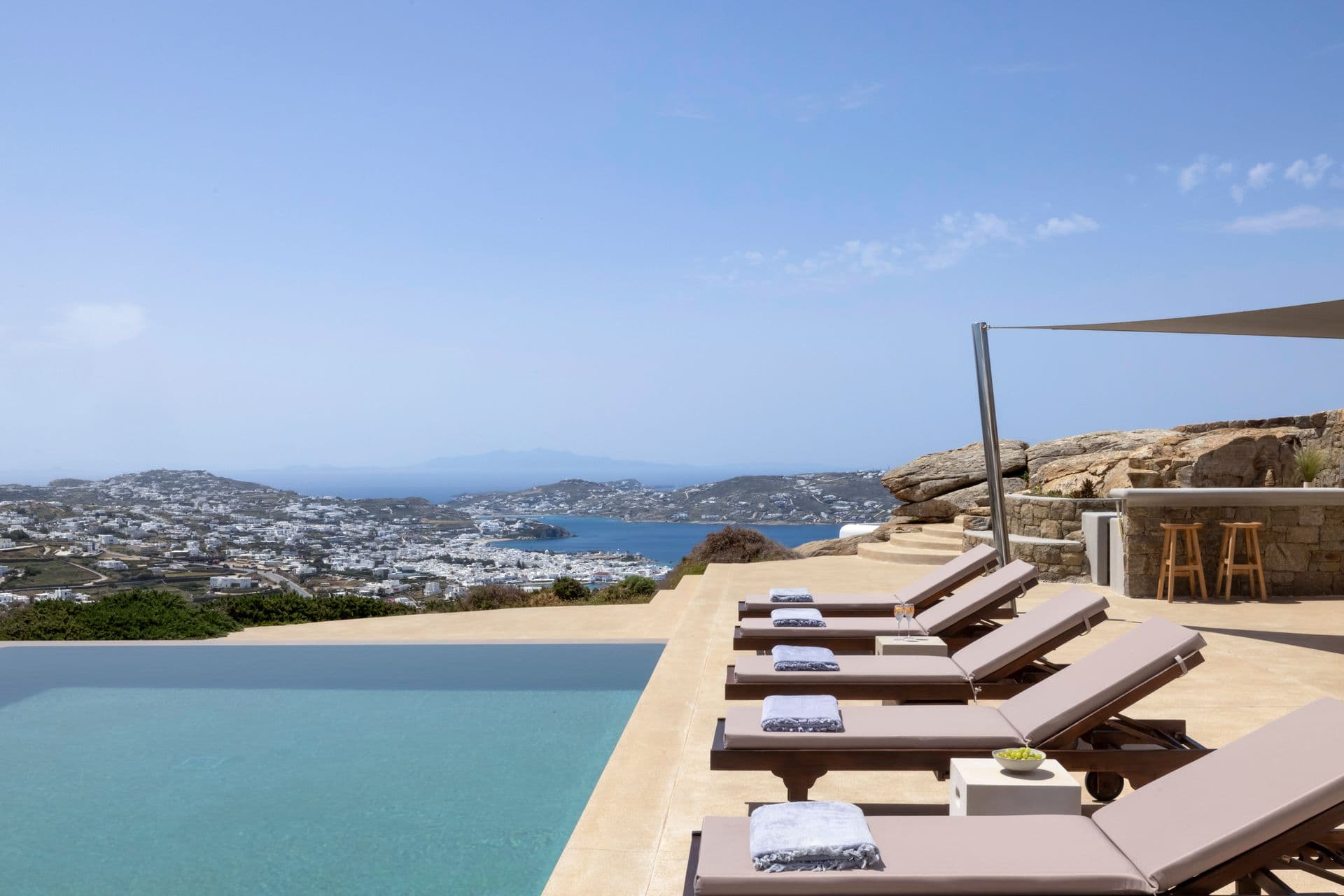 Row of sun loungers along the edge of the infinity pool with panoramic sea views
