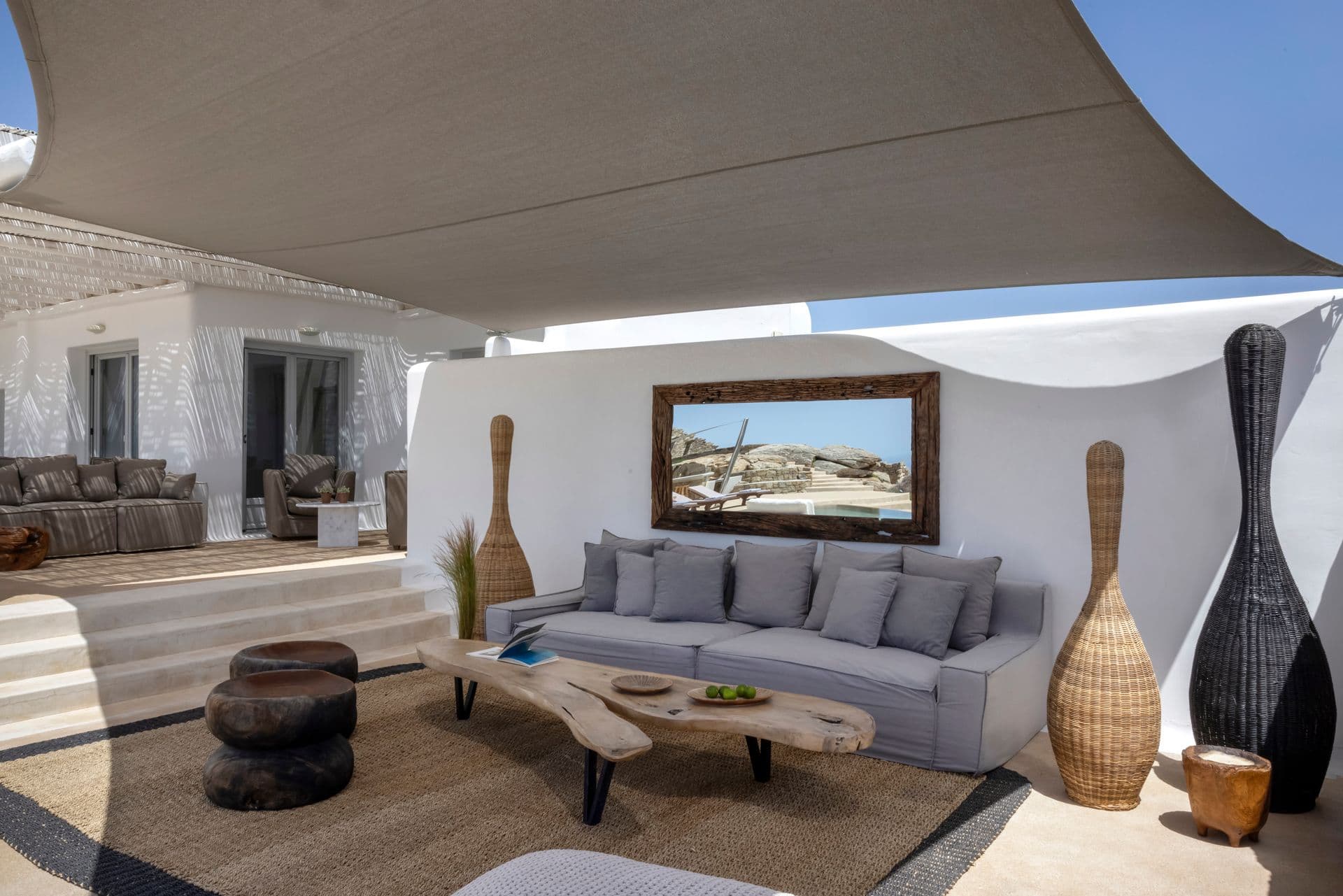 Indoor-outdoor living room with grey sofas set against an exposed stone wall