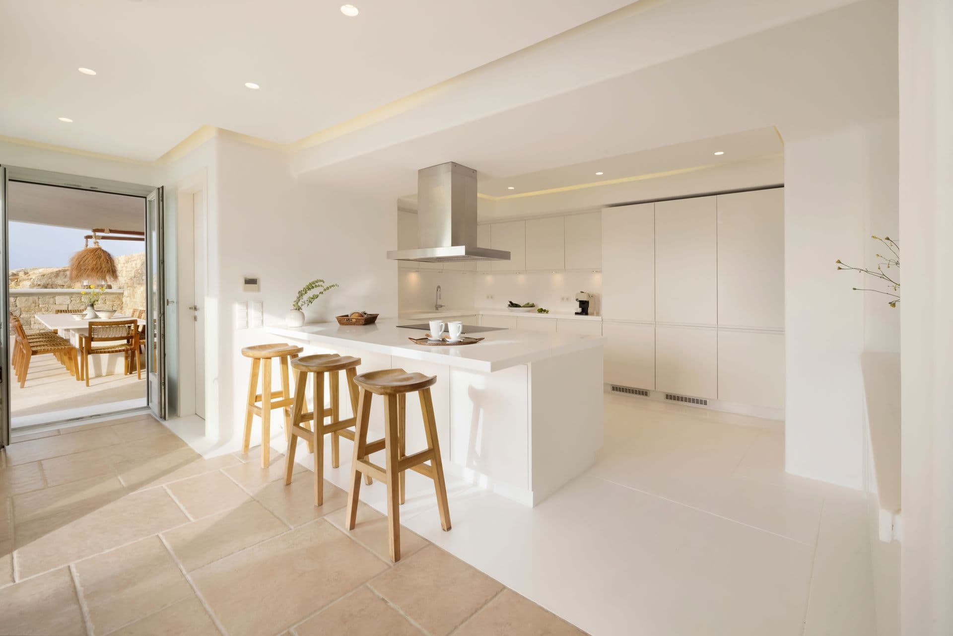Sleek white open-plan kitchen with island seating and a full-height extractor hood