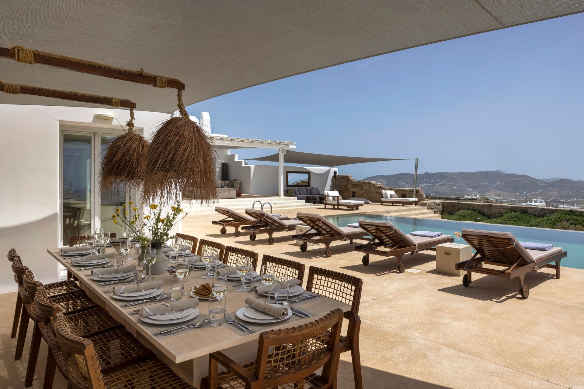 Poolside dining table set for ten beneath a shaded pergola