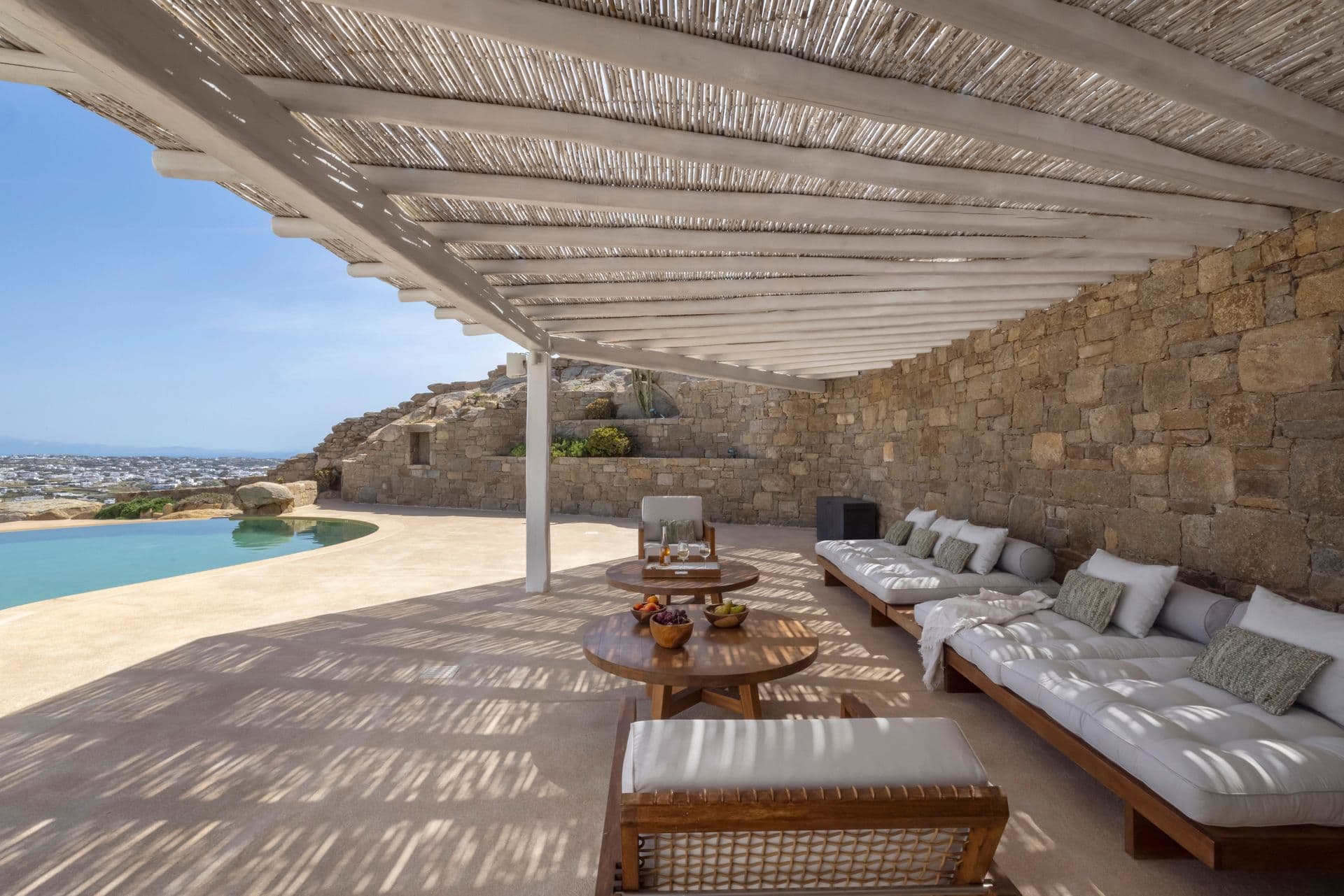 Shaded outdoor lounge with sofas and coffee table overlooking the sea