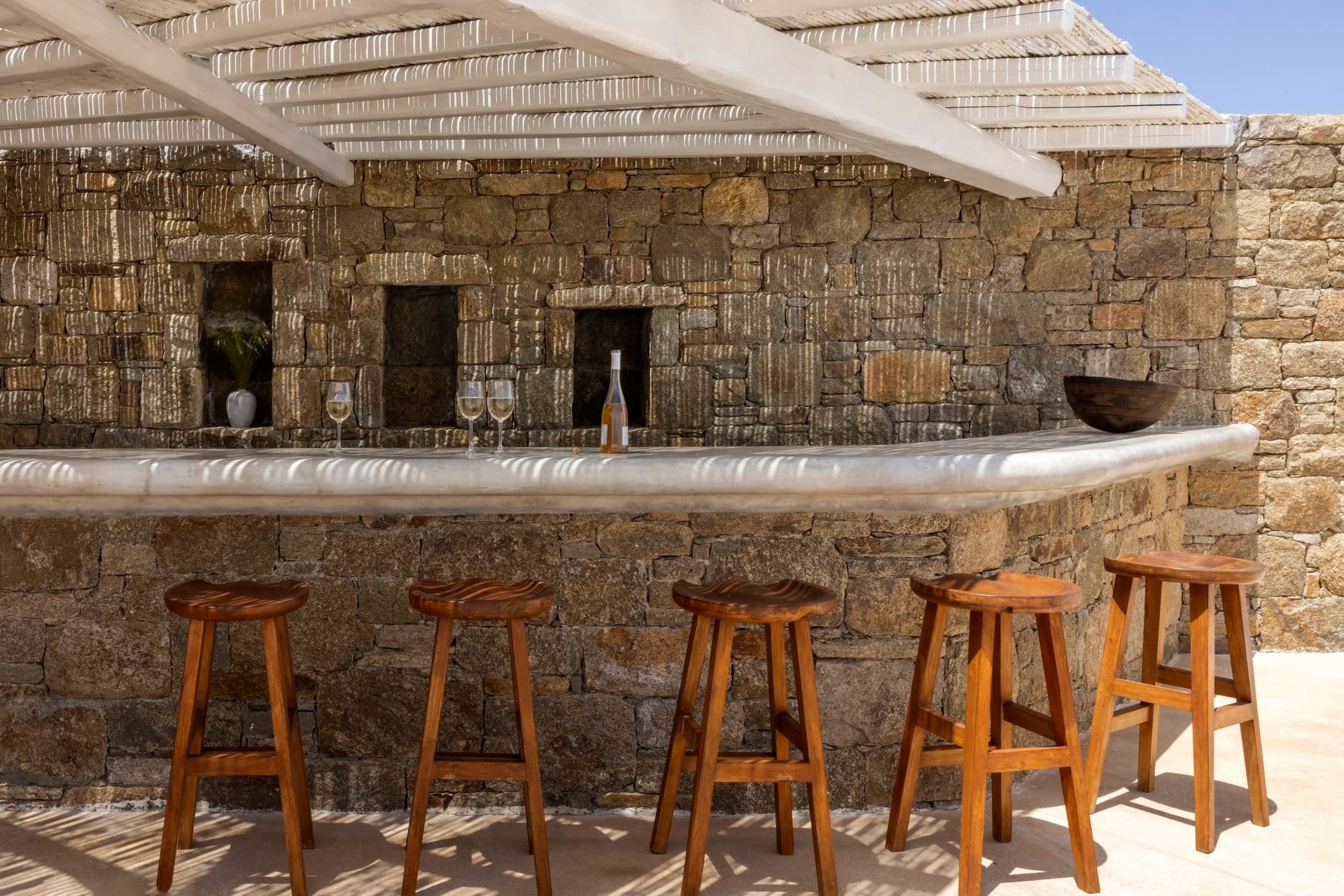 Stone-built outdoor bar with wooden stools set into the terrace wall