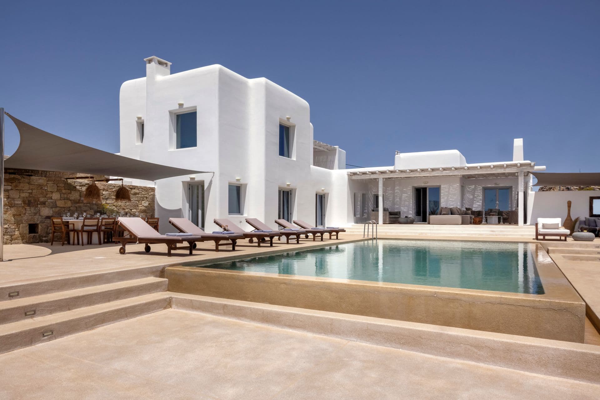 Stone and whitewashed villa facade with covered terrace and pool