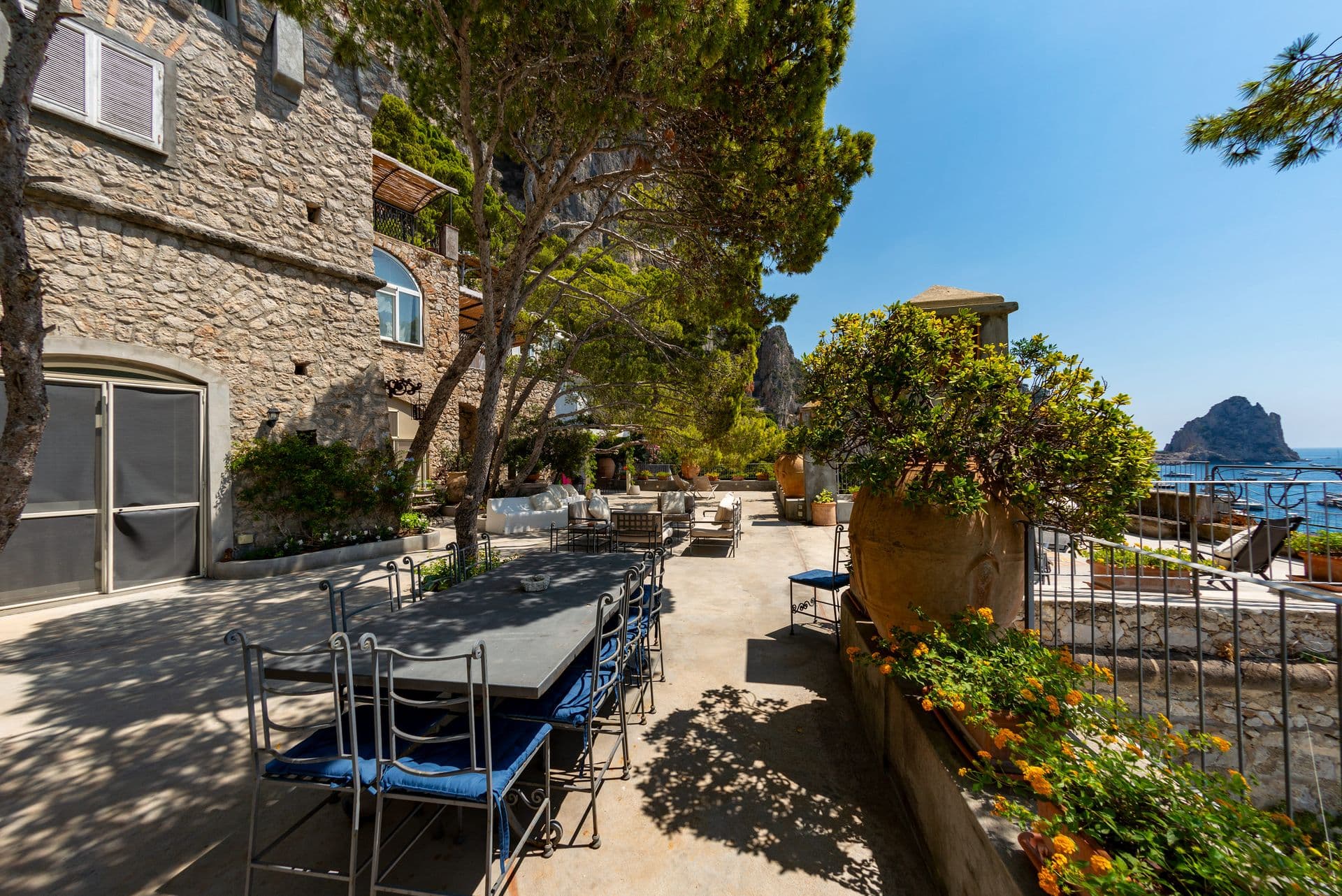 Outdoor dining table beside the stone villa and flowering garden at Faraglioni Frills, Capri