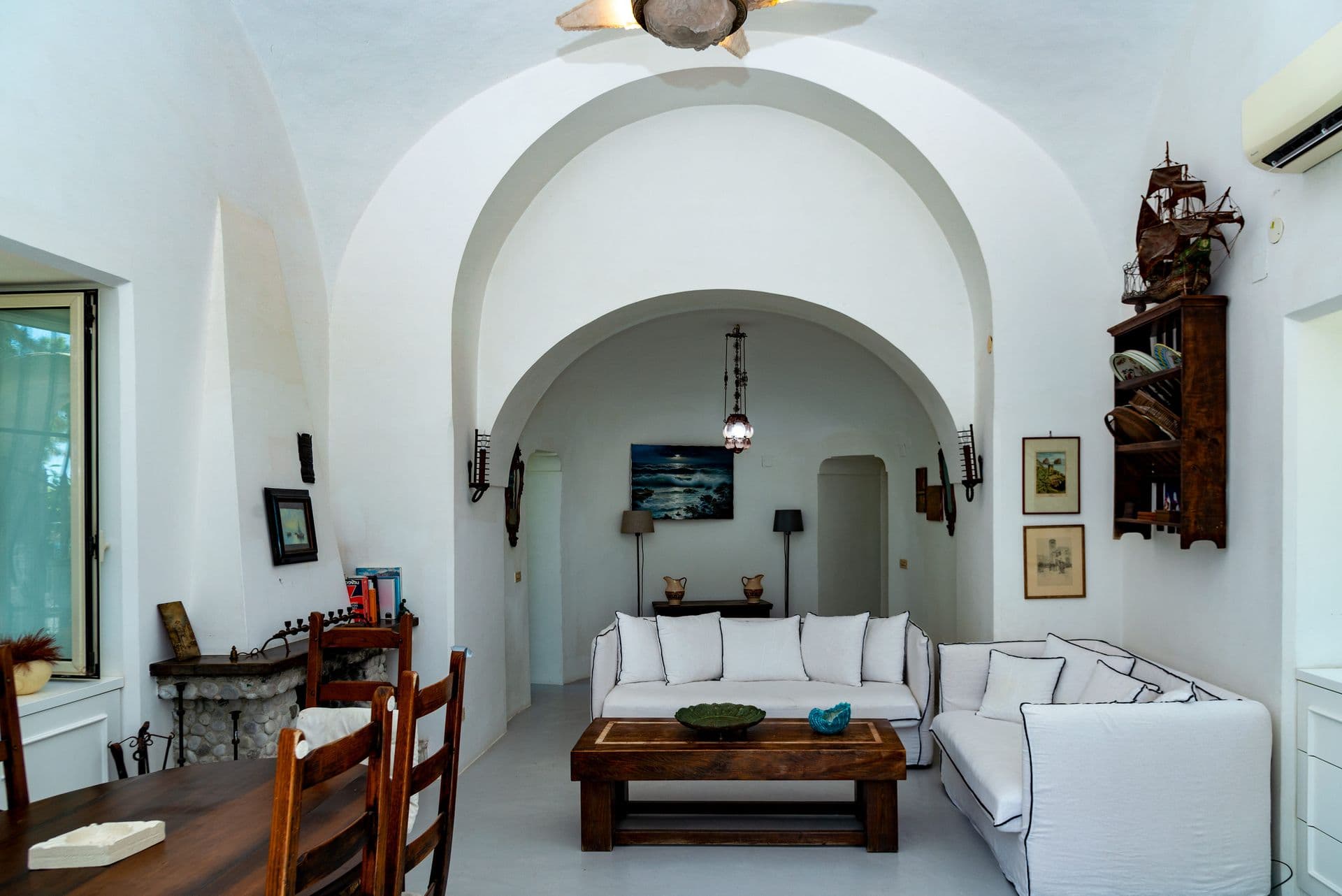 Vaulted white living room with sofas and antique furniture at Faraglioni Frills, Capri