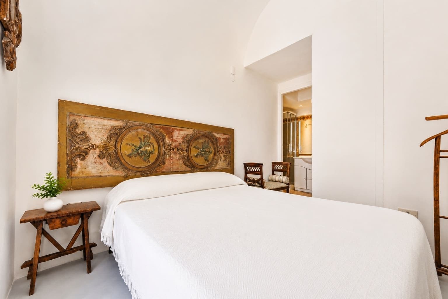 Vaulted bedroom with a tapestry above the bed at Faraglioni Frills, Capri