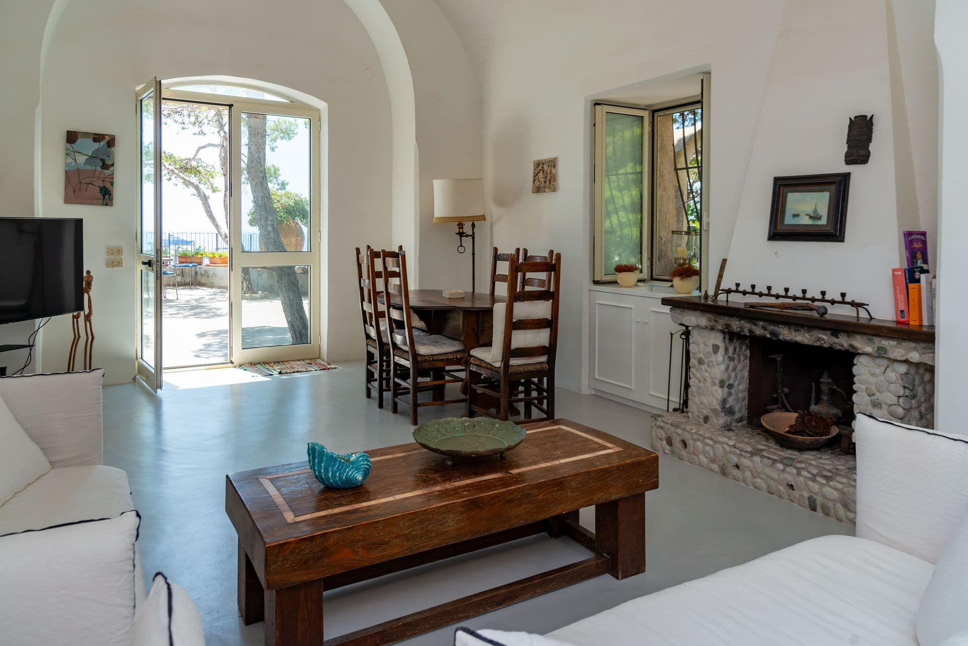 Sitting room with a white sofa and doors opening to the sea terrace at Faraglioni Frills, Capri