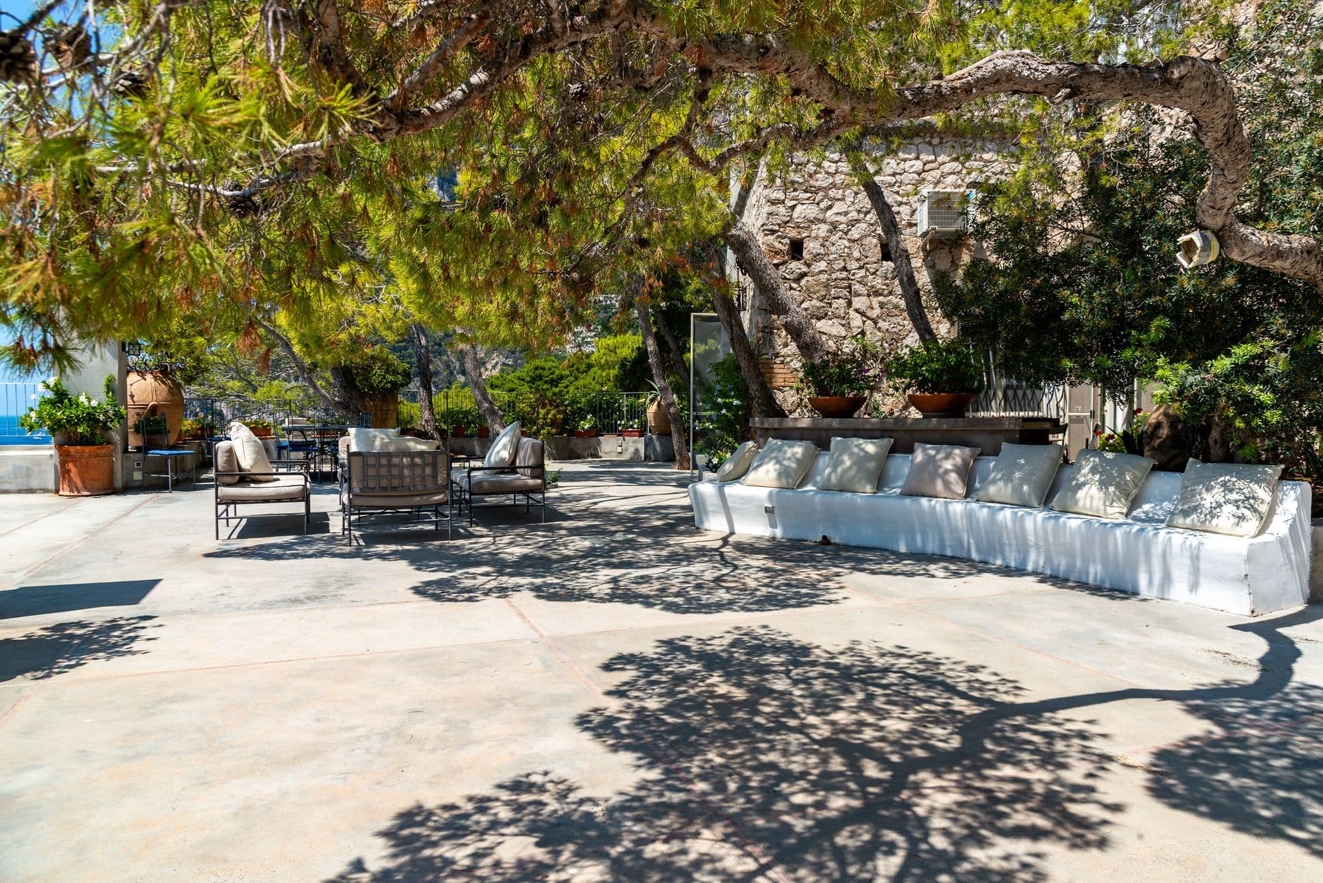 Pine-shaded terrace with a white banquette facing the Faraglioni at Faraglioni Frills, Capri