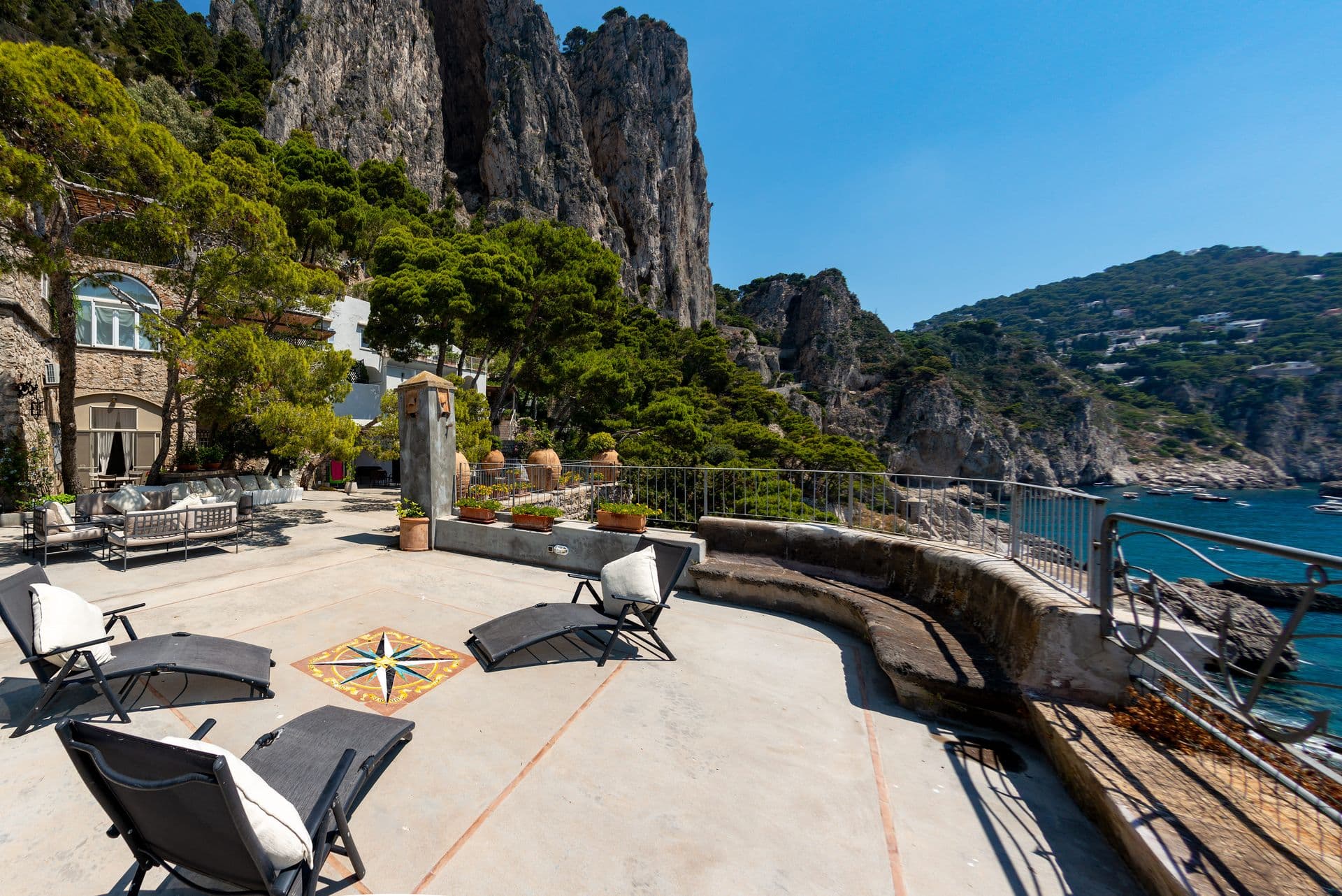 Stone villa on the cliffside with the Capri coastline behind at Faraglioni Frills, Capri