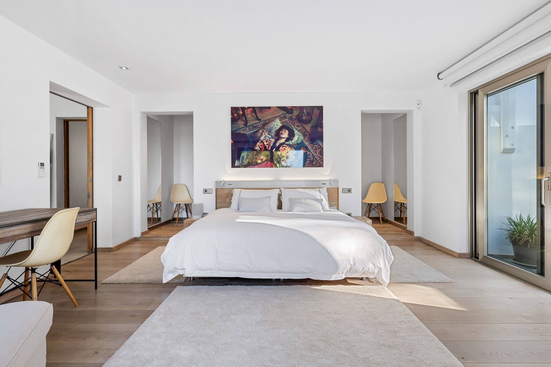 Bedroom with colourful artwork above the bed and wood panelled doors.