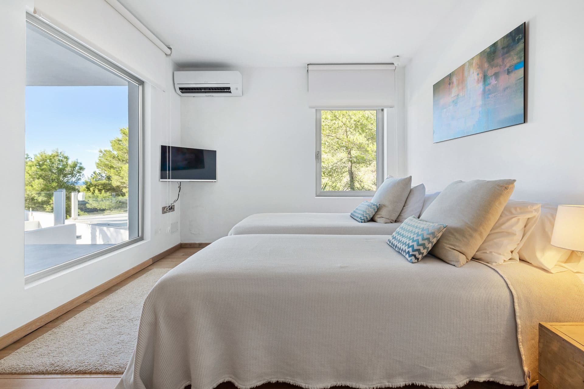 Twin bedroom with sea views through the window and pale linens.