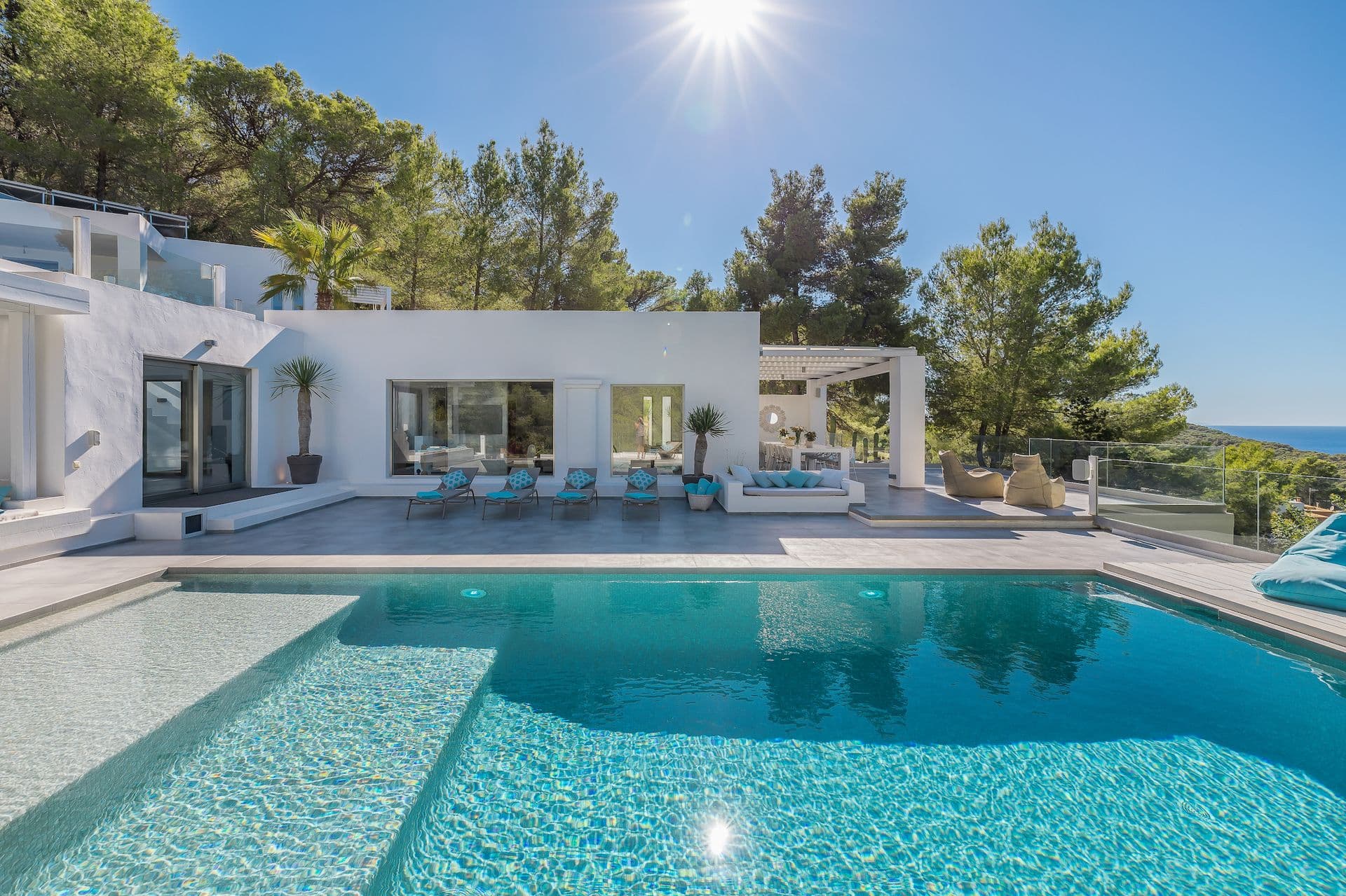 Aerial view of The Balearic Beat's white villa and pool framed by Mediterranean pine trees.