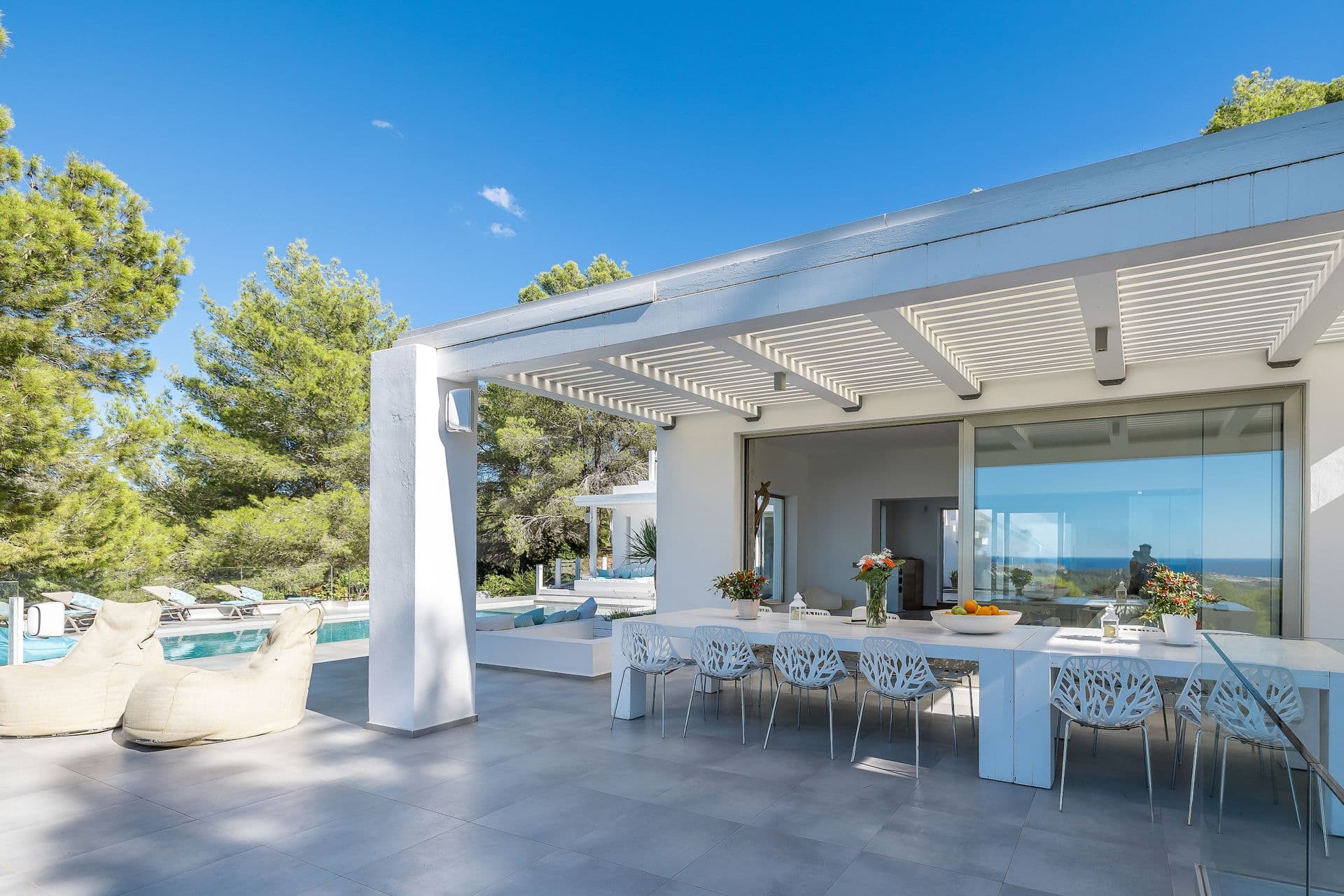 Covered pergola terrace with a long dining table for alfresco meals.