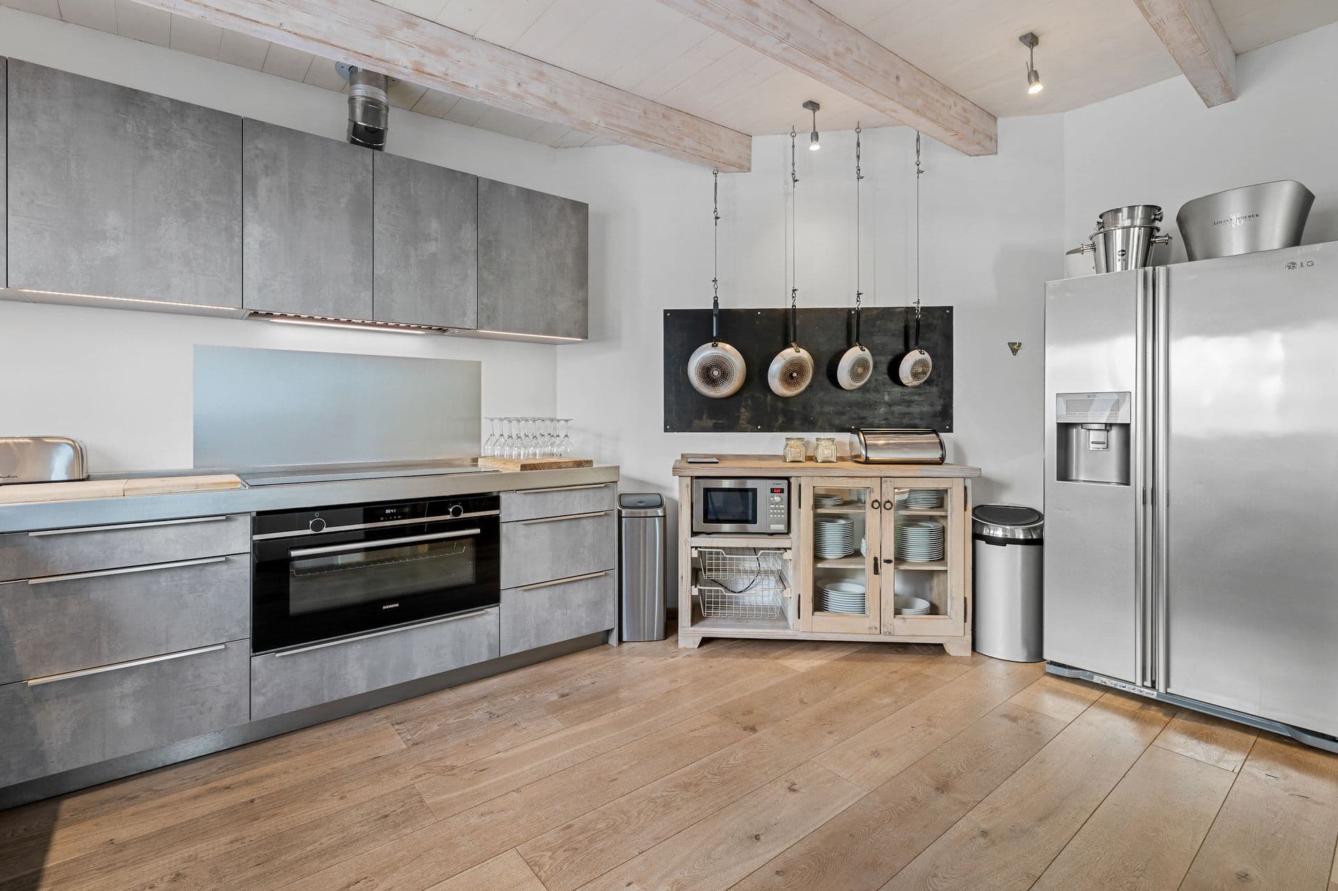 Kitchen run with a stainless steel fridge freezer and integrated ovens.