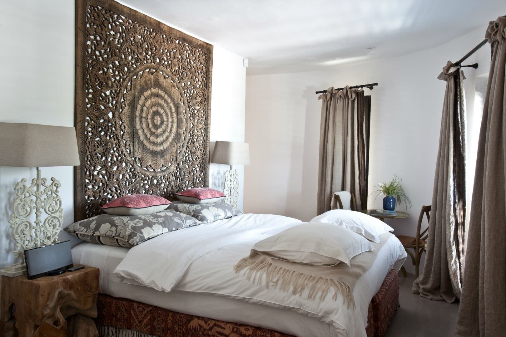 Bedroom with a large carved mandala panel headboard at Cicadas Sway, Ibiza