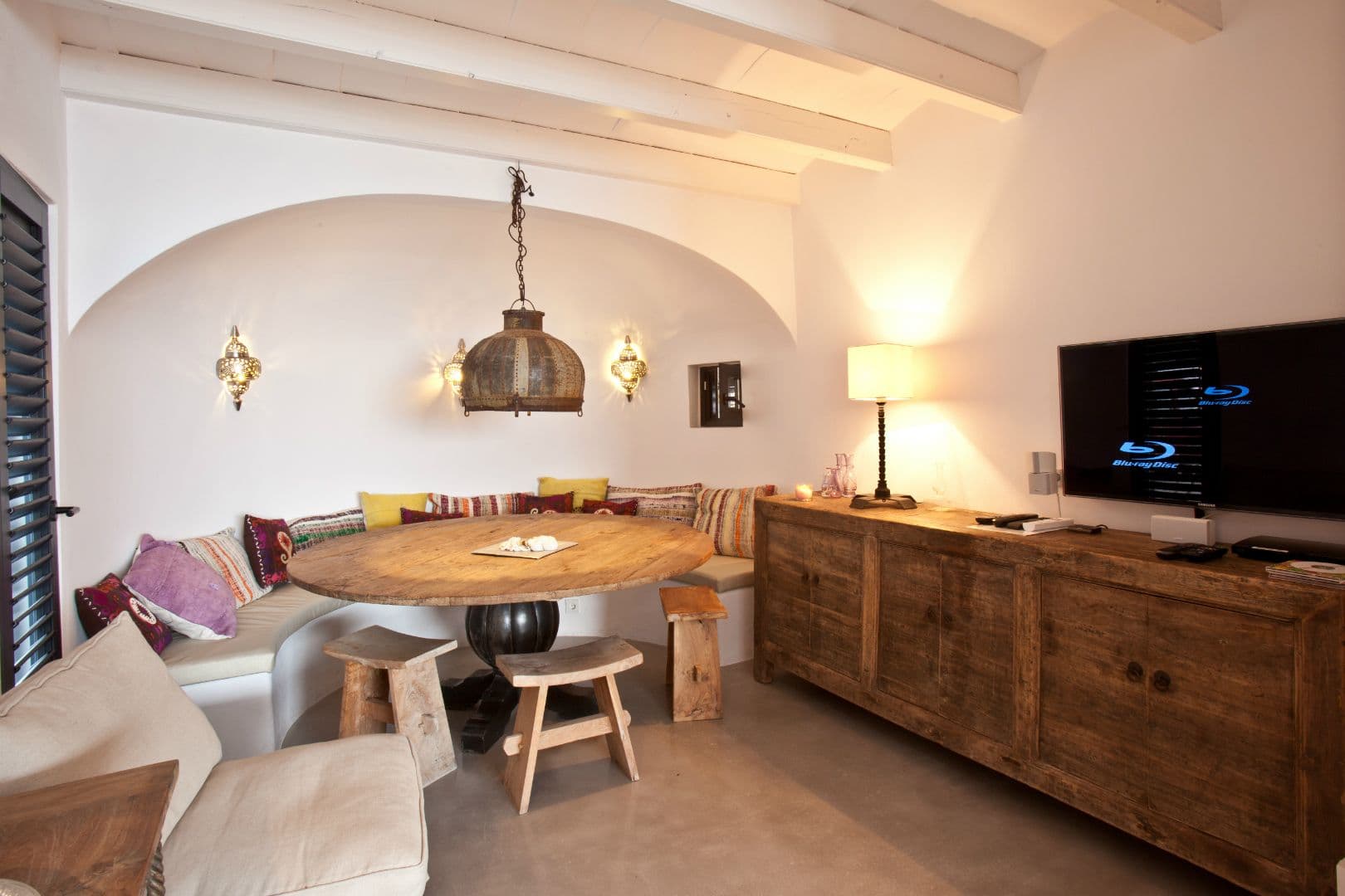 Dining snug with a curved banquette and round timber table at Cicadas Sway, Ibiza