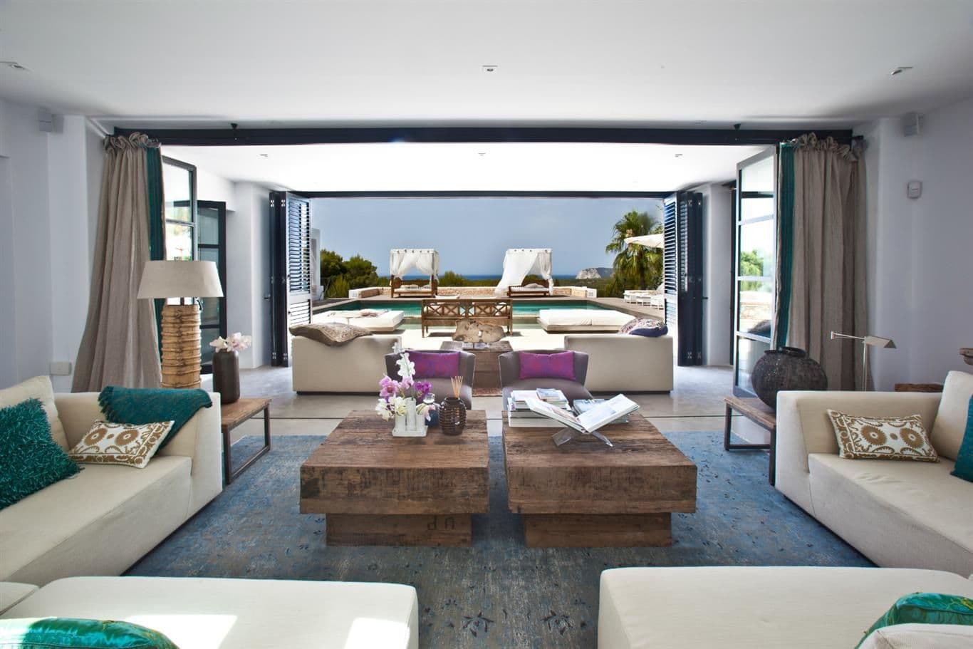 Living room with cream sofas, turquoise accents and folding doors to the pool at Cicadas Sway, Ibiza