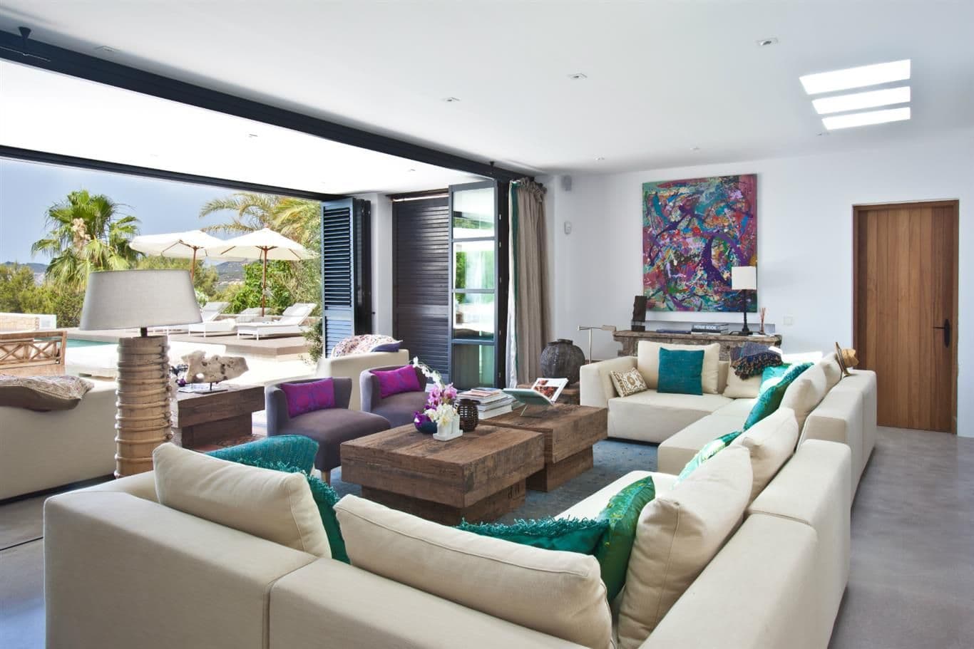 Living lounge with cream sofas and artwork opening to the palms and pool at Cicadas Sway, Ibiza