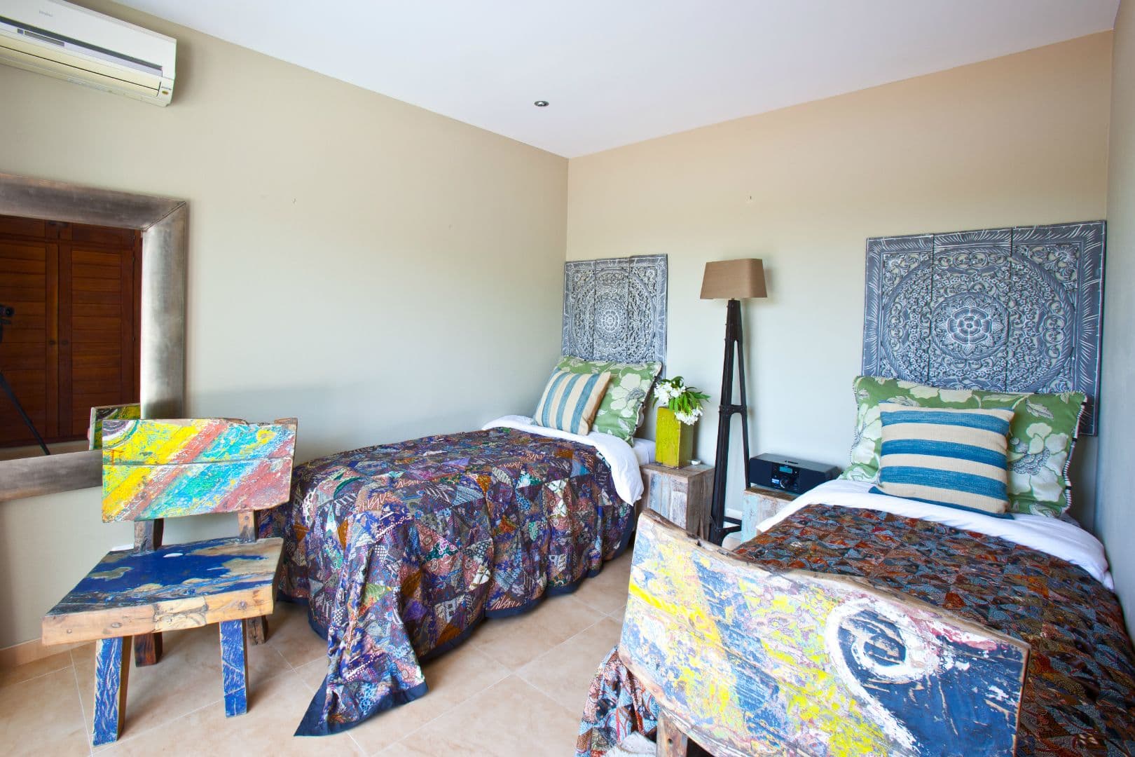 Twin bedroom with carved blue panel headboards and colourful throws at Cicadas Sway, Ibiza