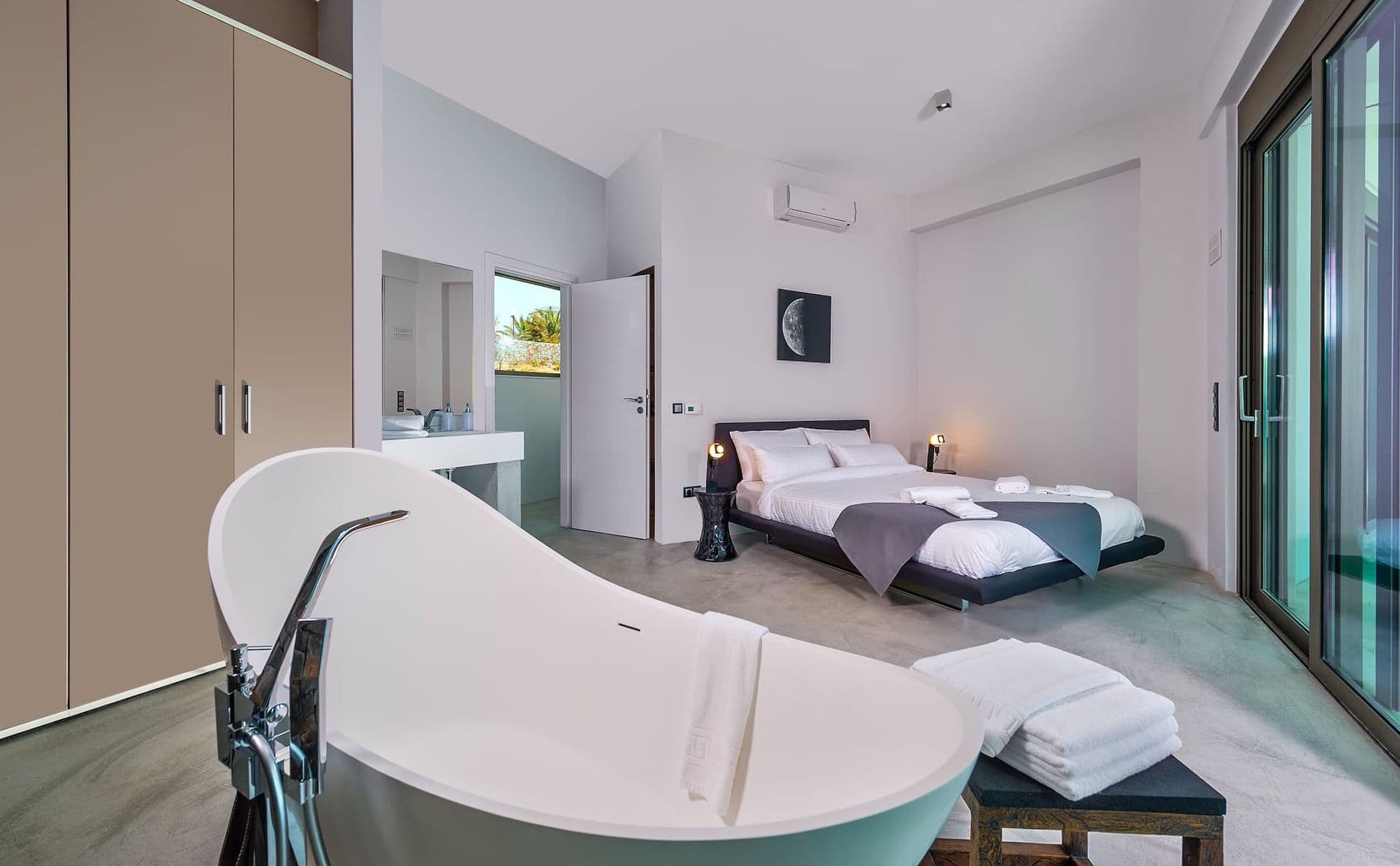 Bedroom suite with a freestanding oval bathtub set beside the bed.