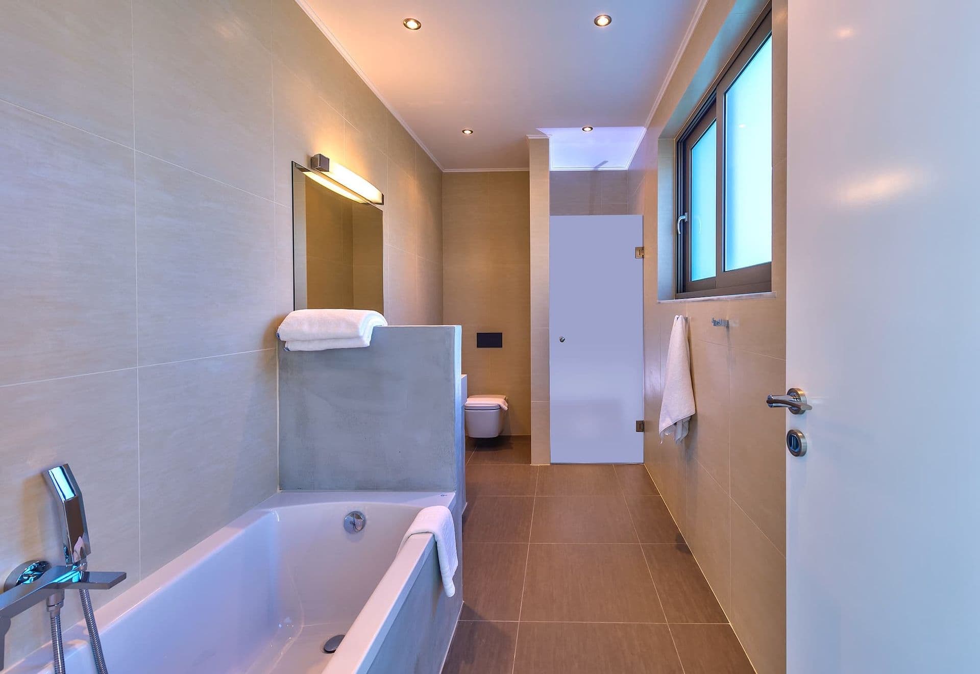 Bedroom at twilight with sliding doors open to the illuminated sea view.