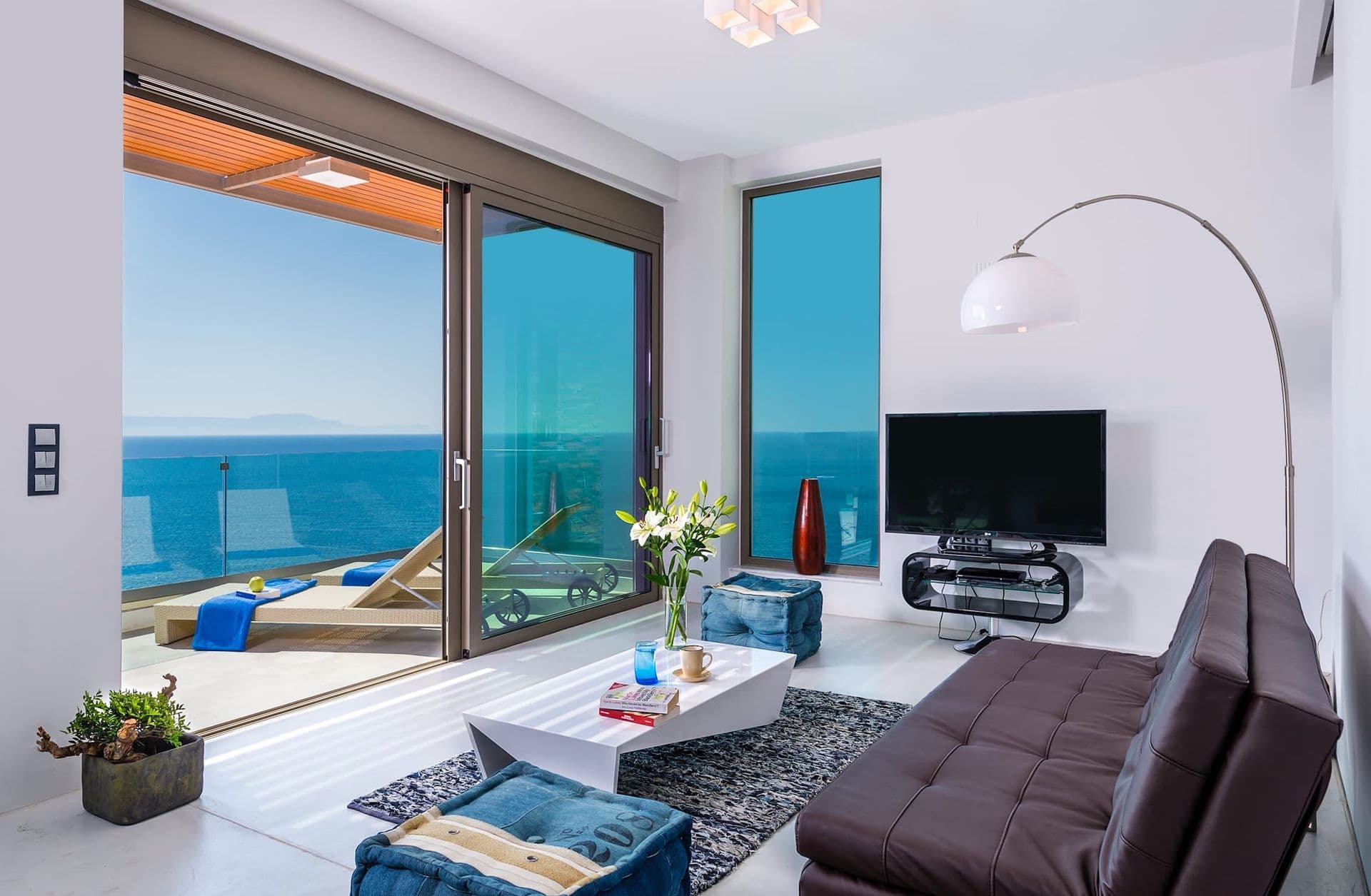 Living room with dark leather sofas and full-height sliding doors framing the sea.