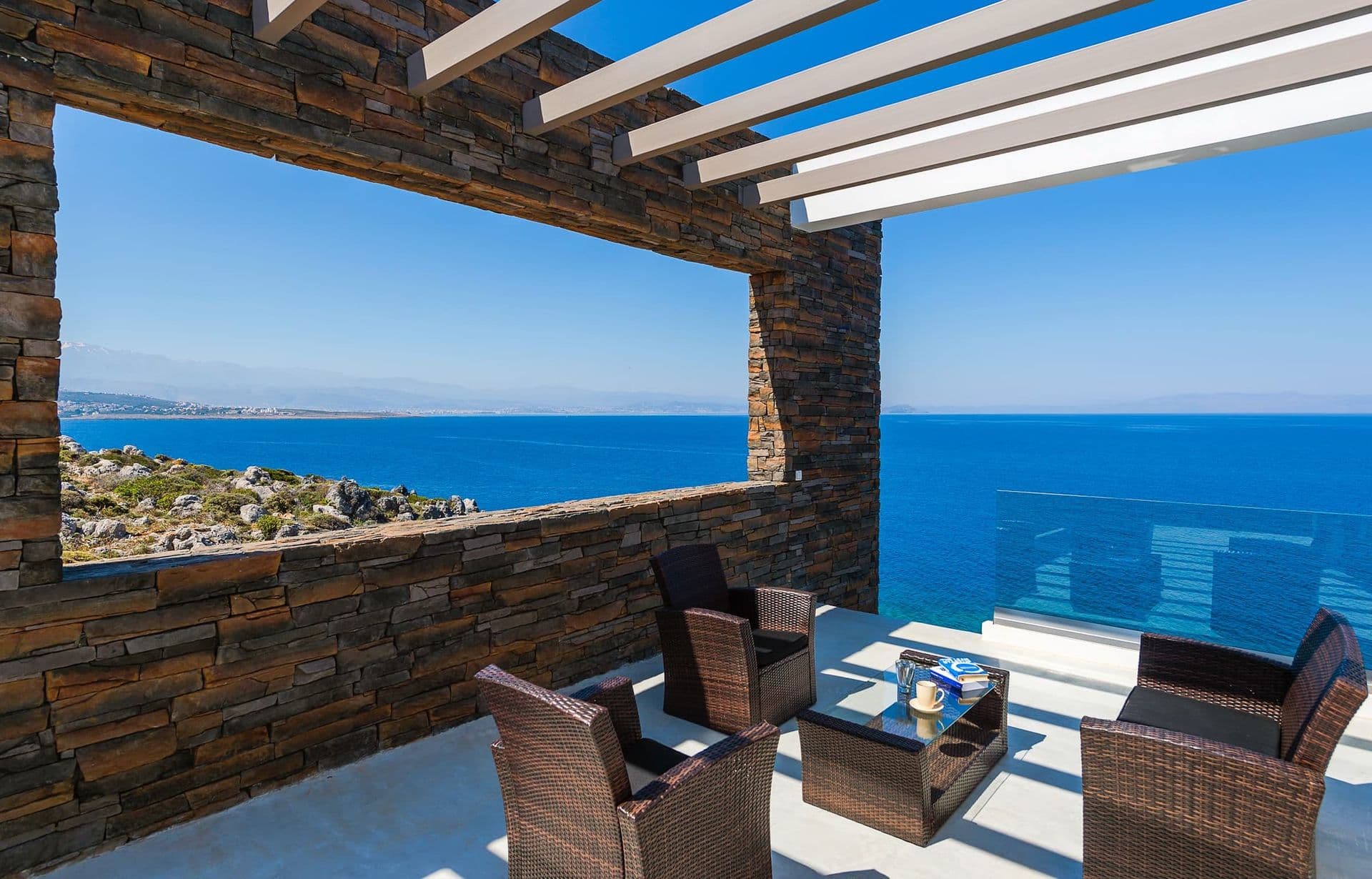 Covered outdoor lounge with rattan seating and an open sea horizon.