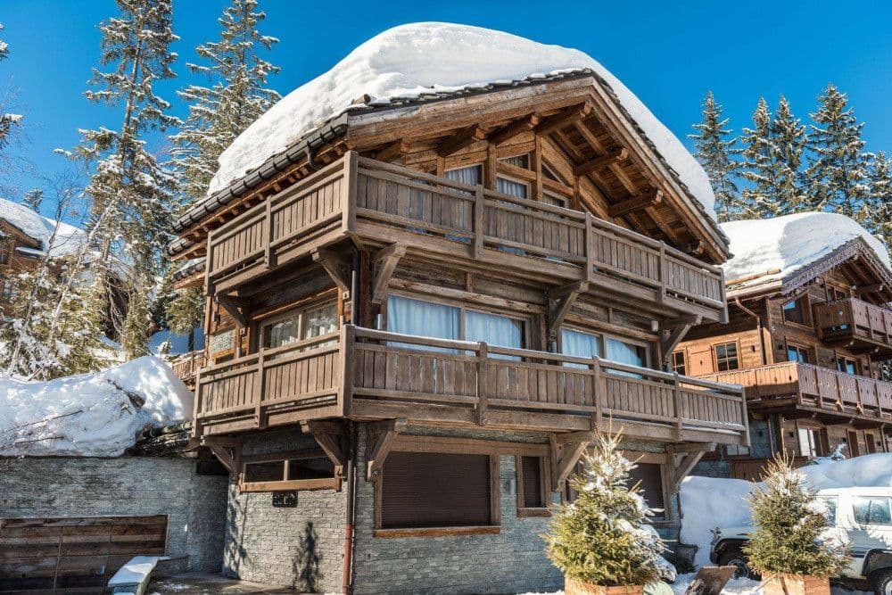 Timber chalet with balconies under deep snow in Courchevel 1850