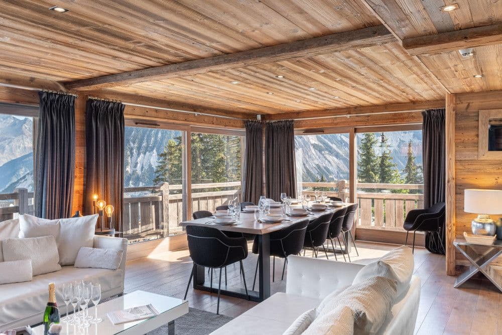 Dining room with a timber table and mountain views at Courchevel 26