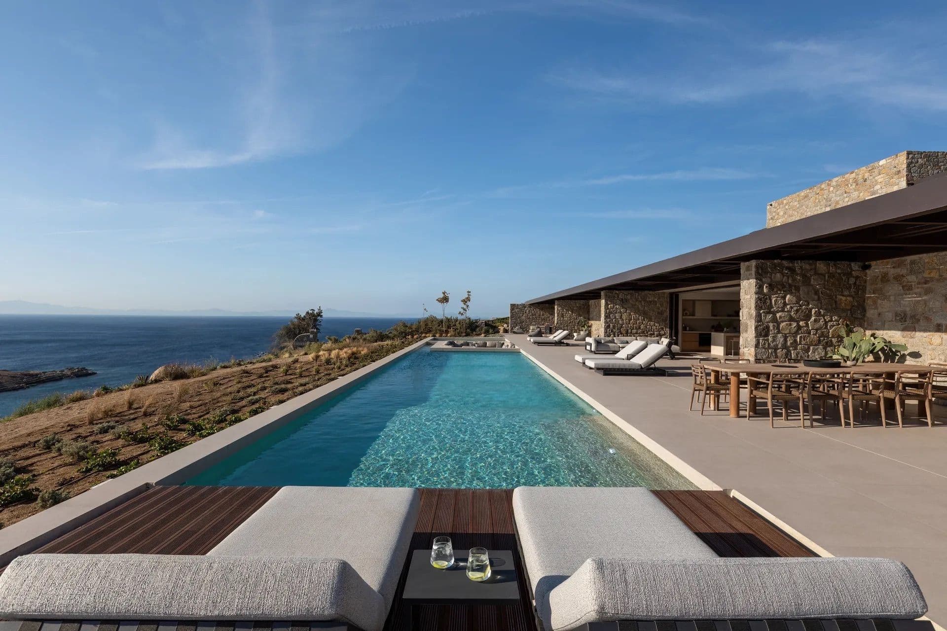 Long infinity pool with poolside dining and lounge seating overlooking the coastline