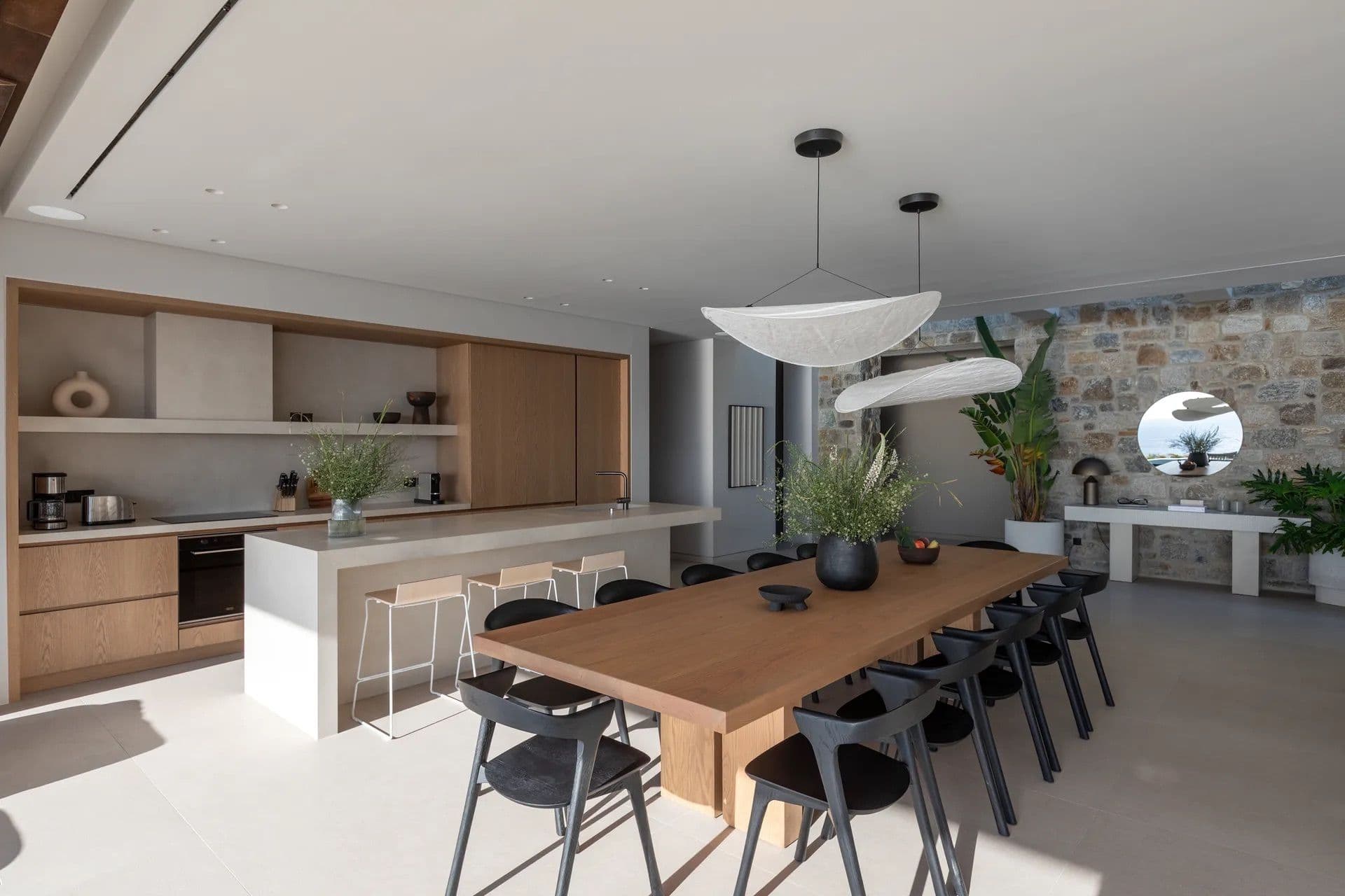 Open-plan wooden kitchen island with black bar stools and dining table