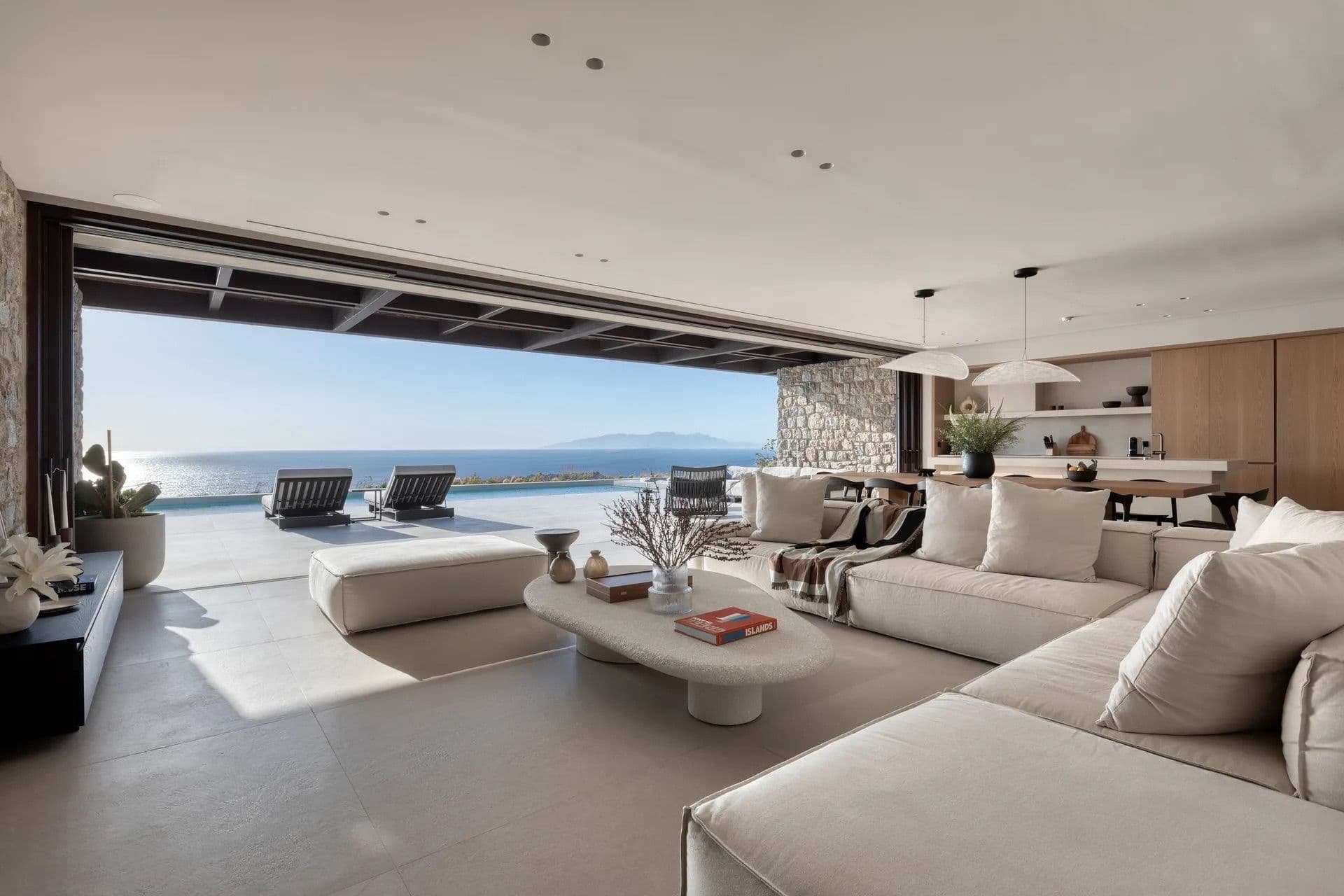 Open-plan living room with folding glass doors onto a terrace and sea view