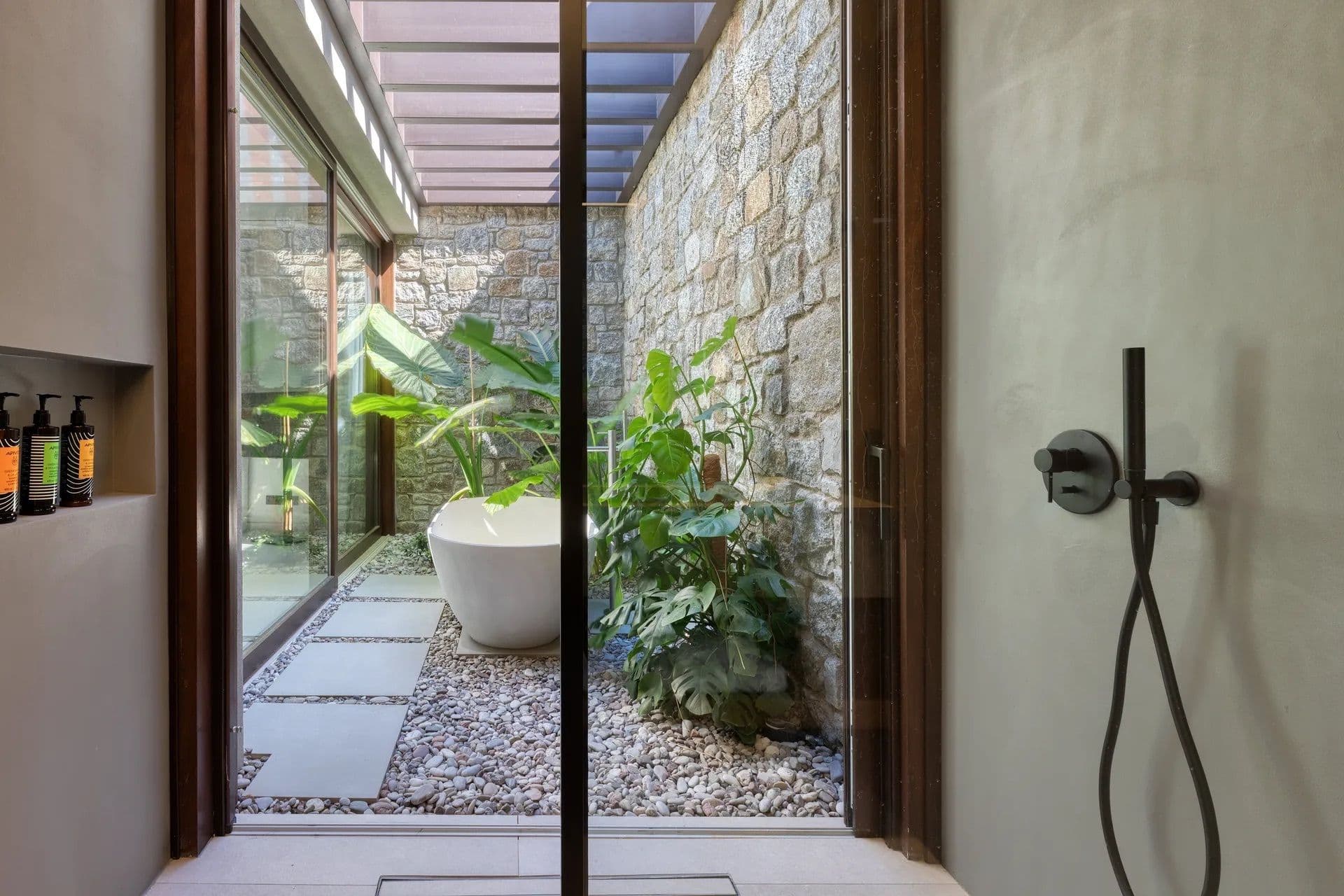 Open-air stone shower corridor lined with tropical plants
