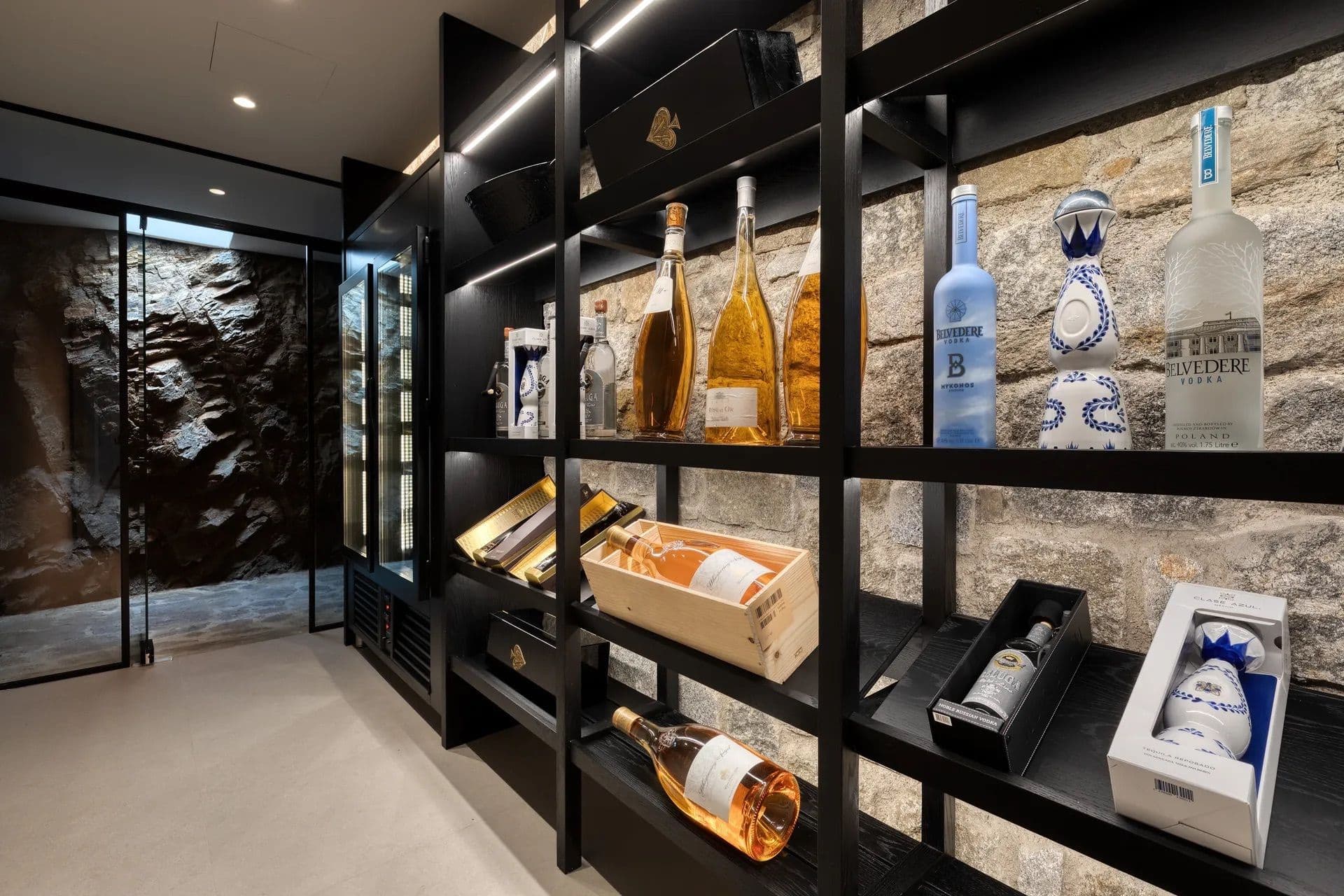 Built-in wine and spirits display shelving set against a stone wall