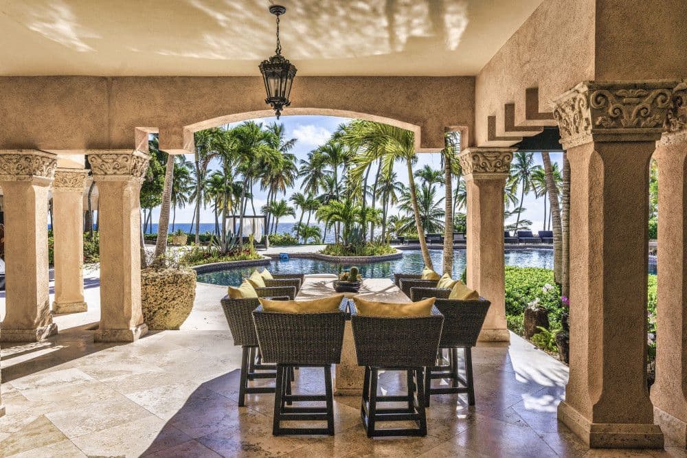 Covered alfresco dining terrace framing the pool and palms at Villa Anacaona