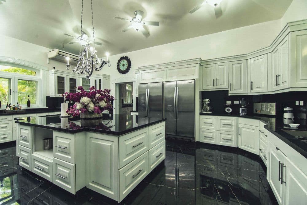 Main kitchen with white cabinetry, granite worktops and a central island