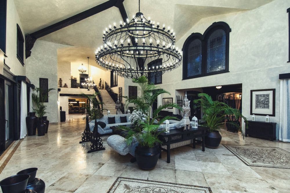 Double-height living hall with an iron chandelier and marble floors